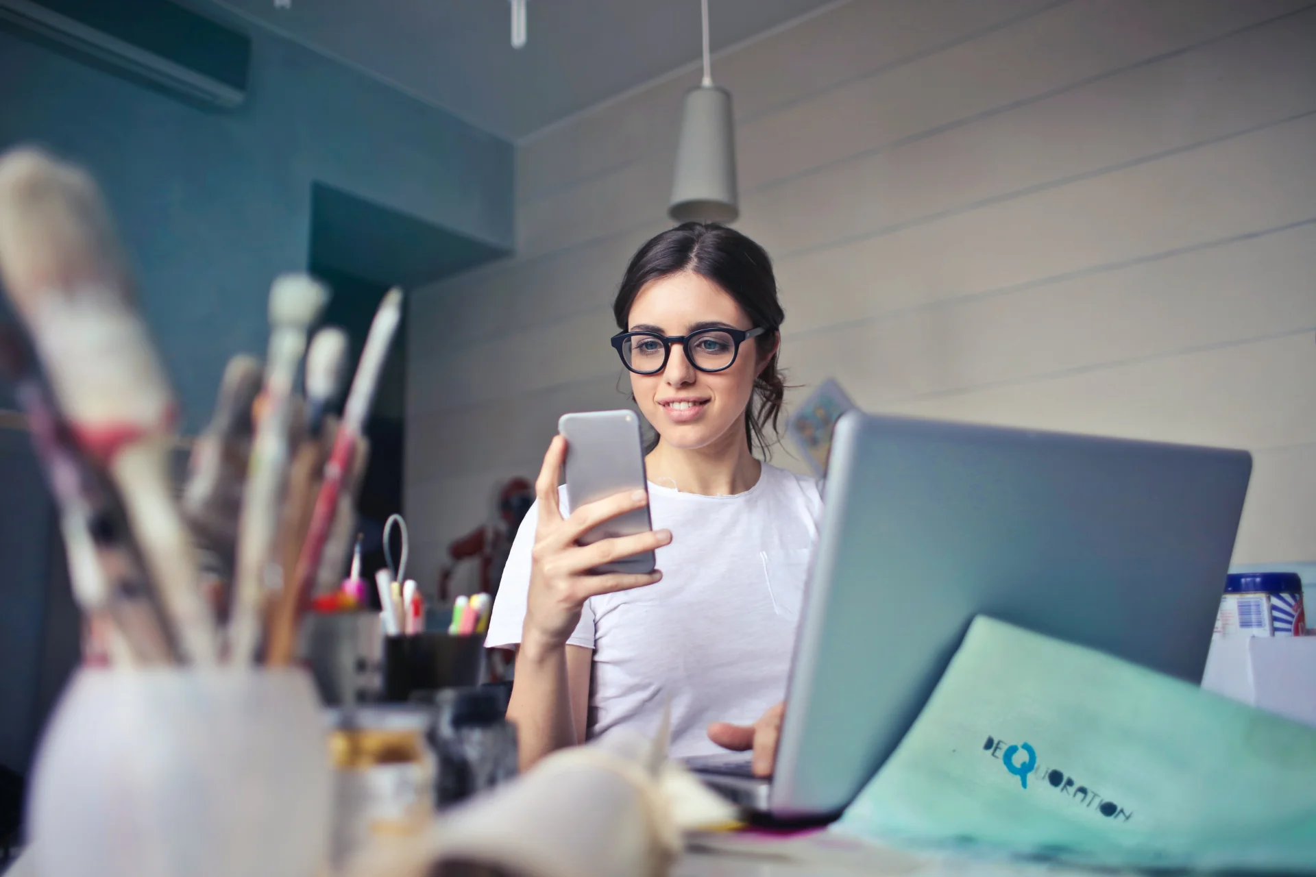 benefity pracownicze młoda kobieta przy biurku patrzy w telefon