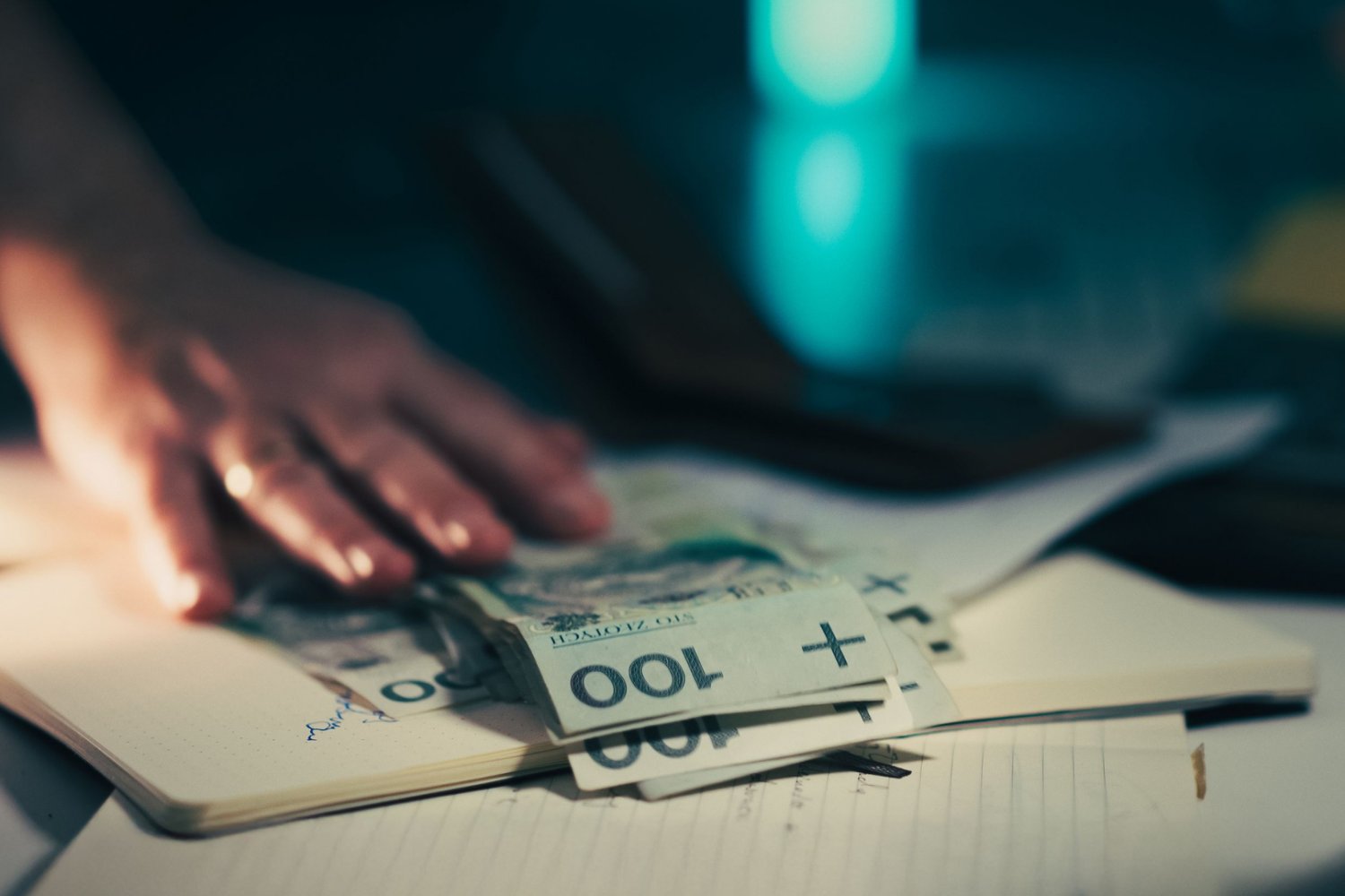 ZUS kompletnie się poddaje. Przestanie ganiać Polaków ws. długów dłoń na banknotach 100-złotowych.