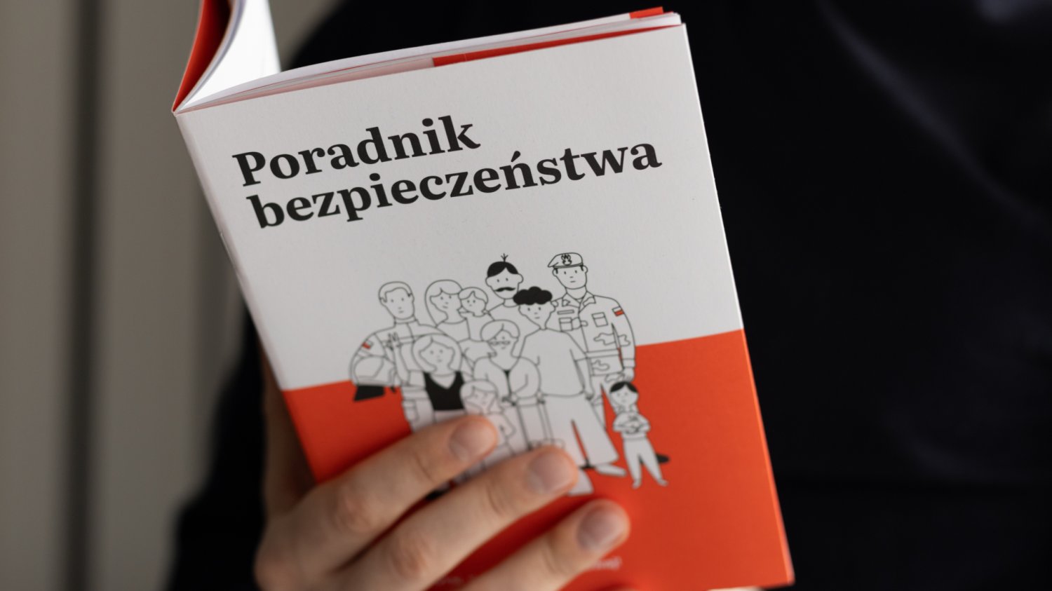 Dłoń trzymająca Poradnik Bezpieczeństwa