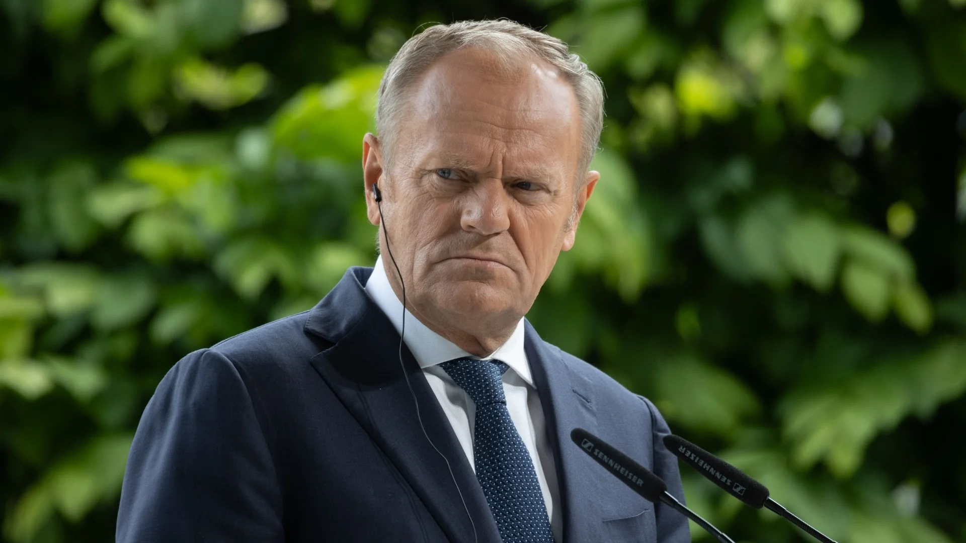 Donald Tusk na tle zielonej roślinności