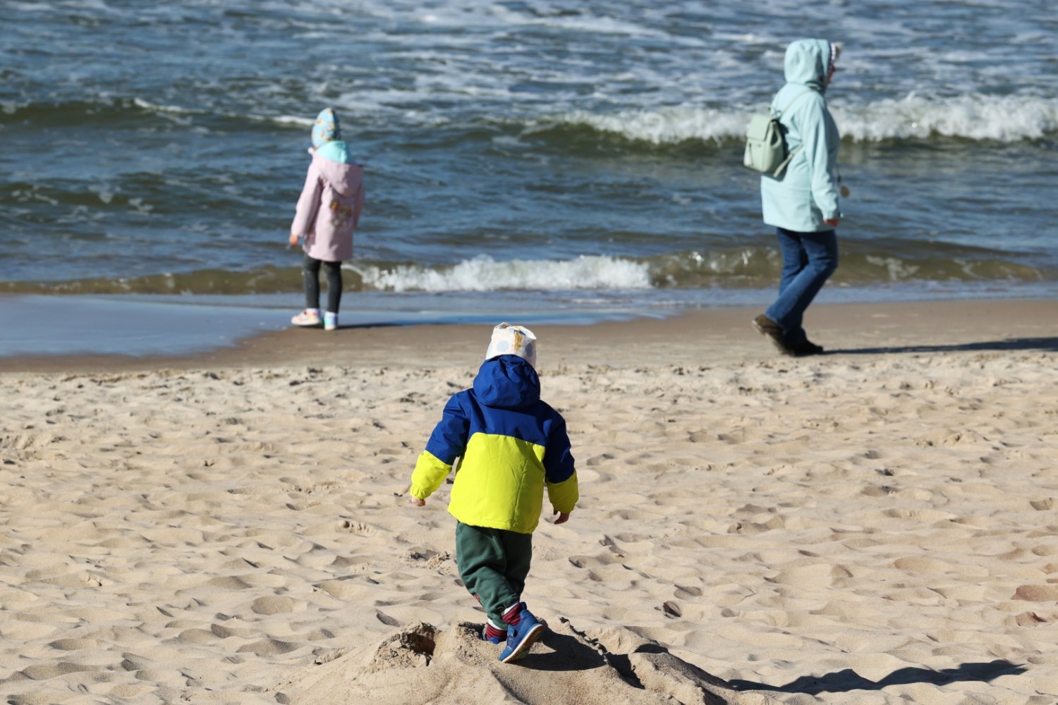 Dzieci z mamą w ciepłych kurtkach na plaży nad morzem Bałtyckim
