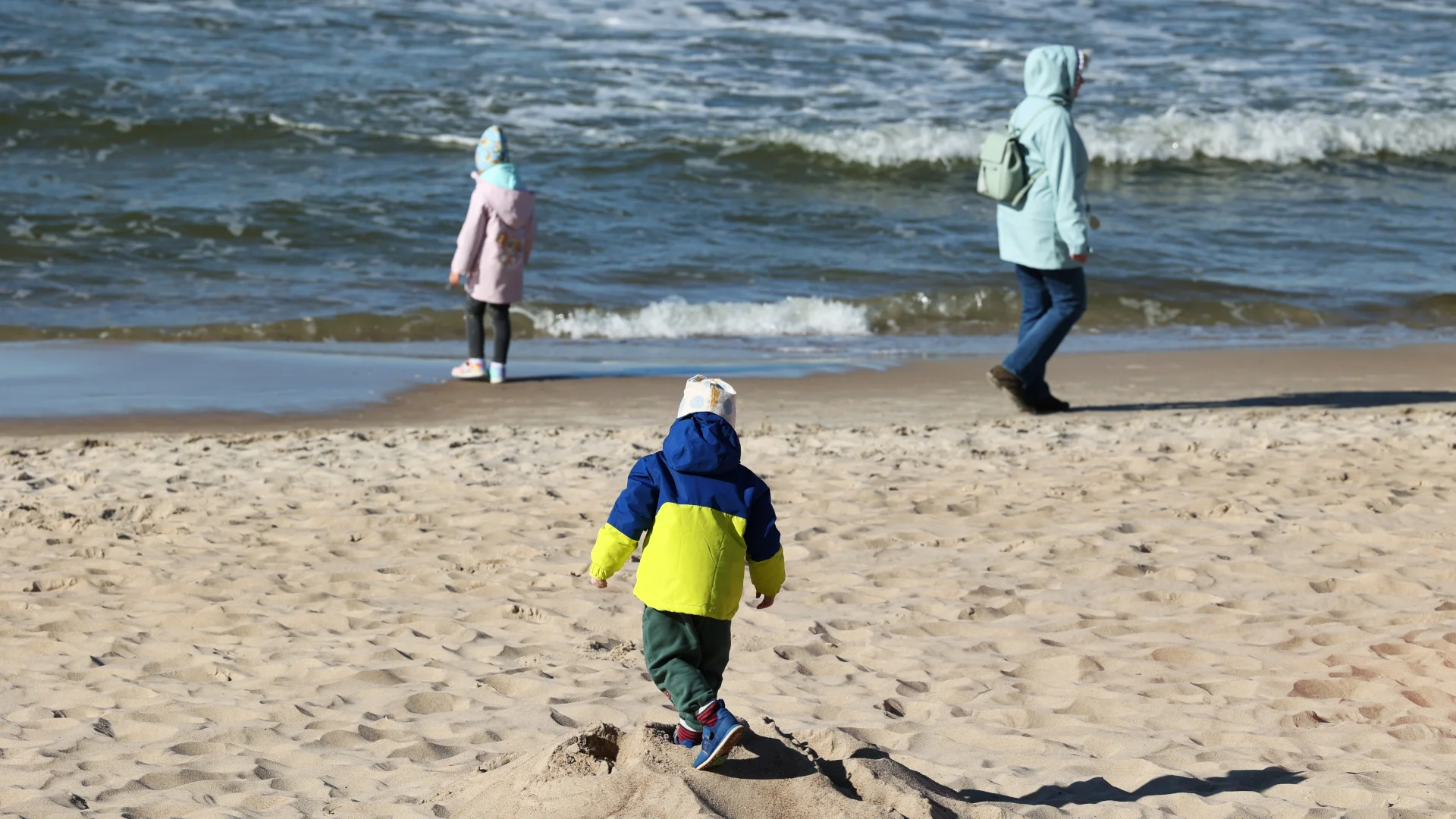 Czy 14 października to dzień wolny? Długi weekend 2026 Dzieci z mamą w ciepłych kurtkach na plaży nad morzem Bałtyckim