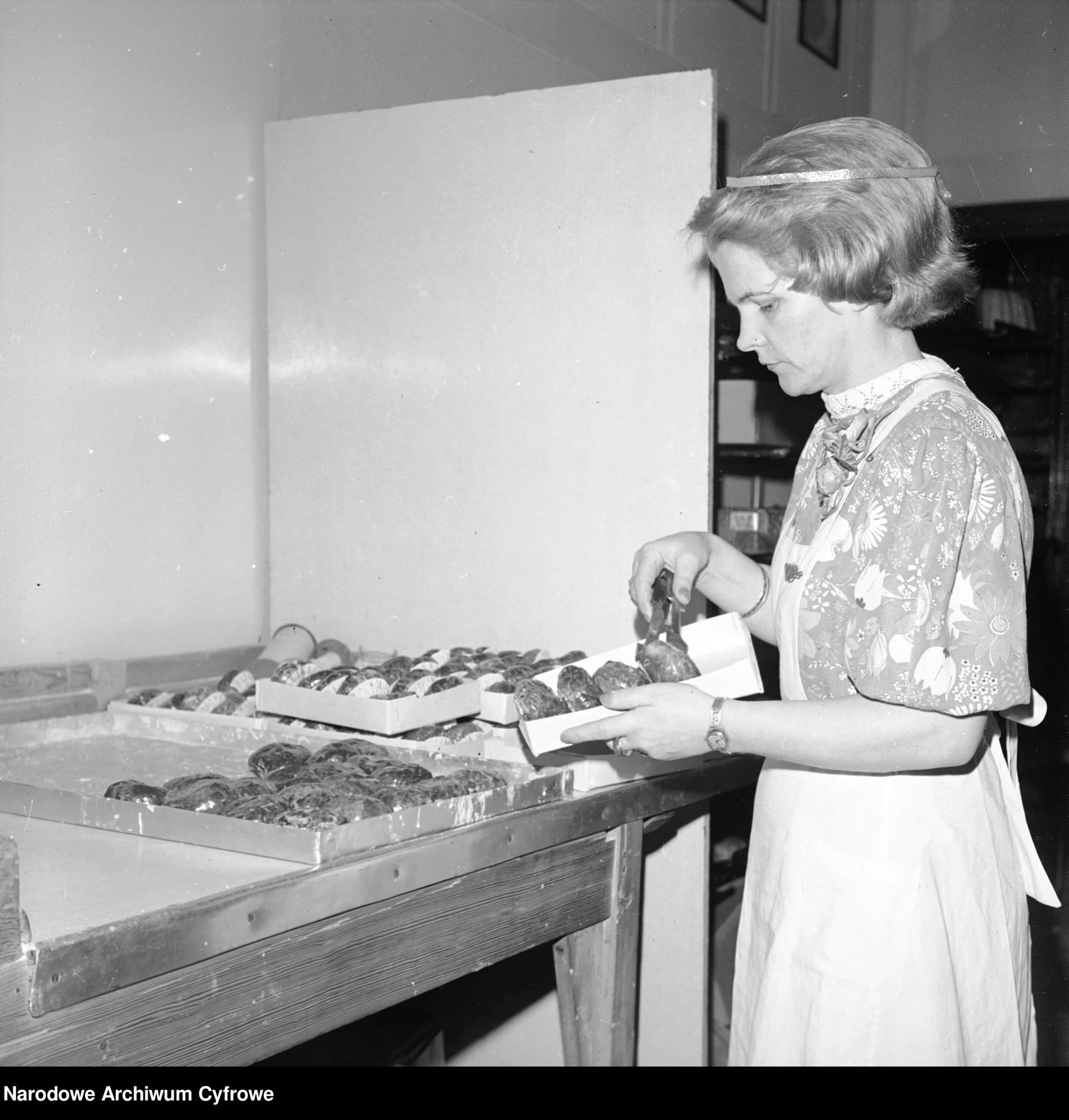 Rok 1978. Sprzedawczyni w cukierni opakowuje pączki przygotowane do sprzedaży.