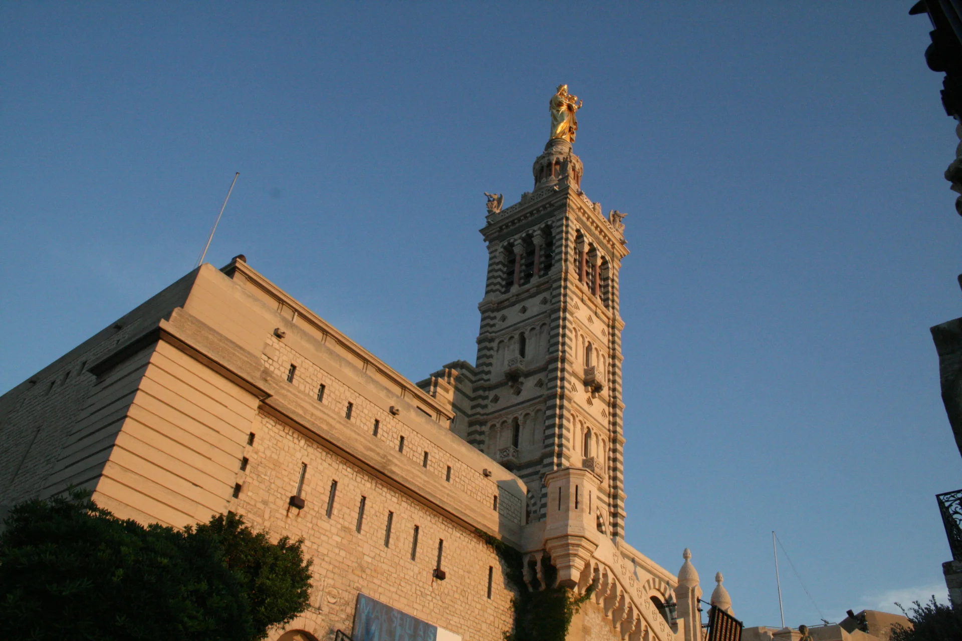 Bazylika Notre Dame de la Garde z gigantyczną złoconą figurą Madonny z Dzieciątkiem. Nocą iluminowana świątynia przypomina latarnię morską.