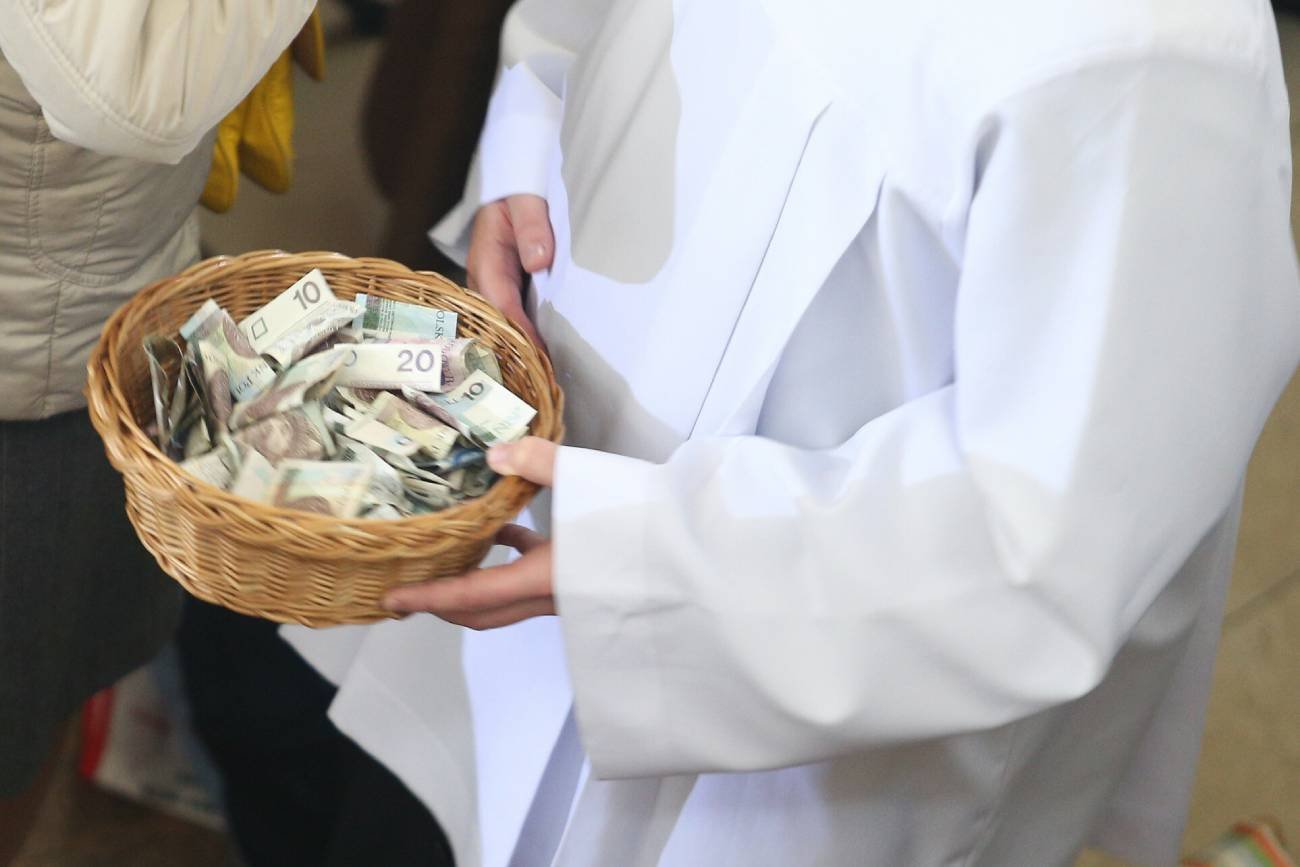 Ksiądz trzymający tacę z pieniędzmi