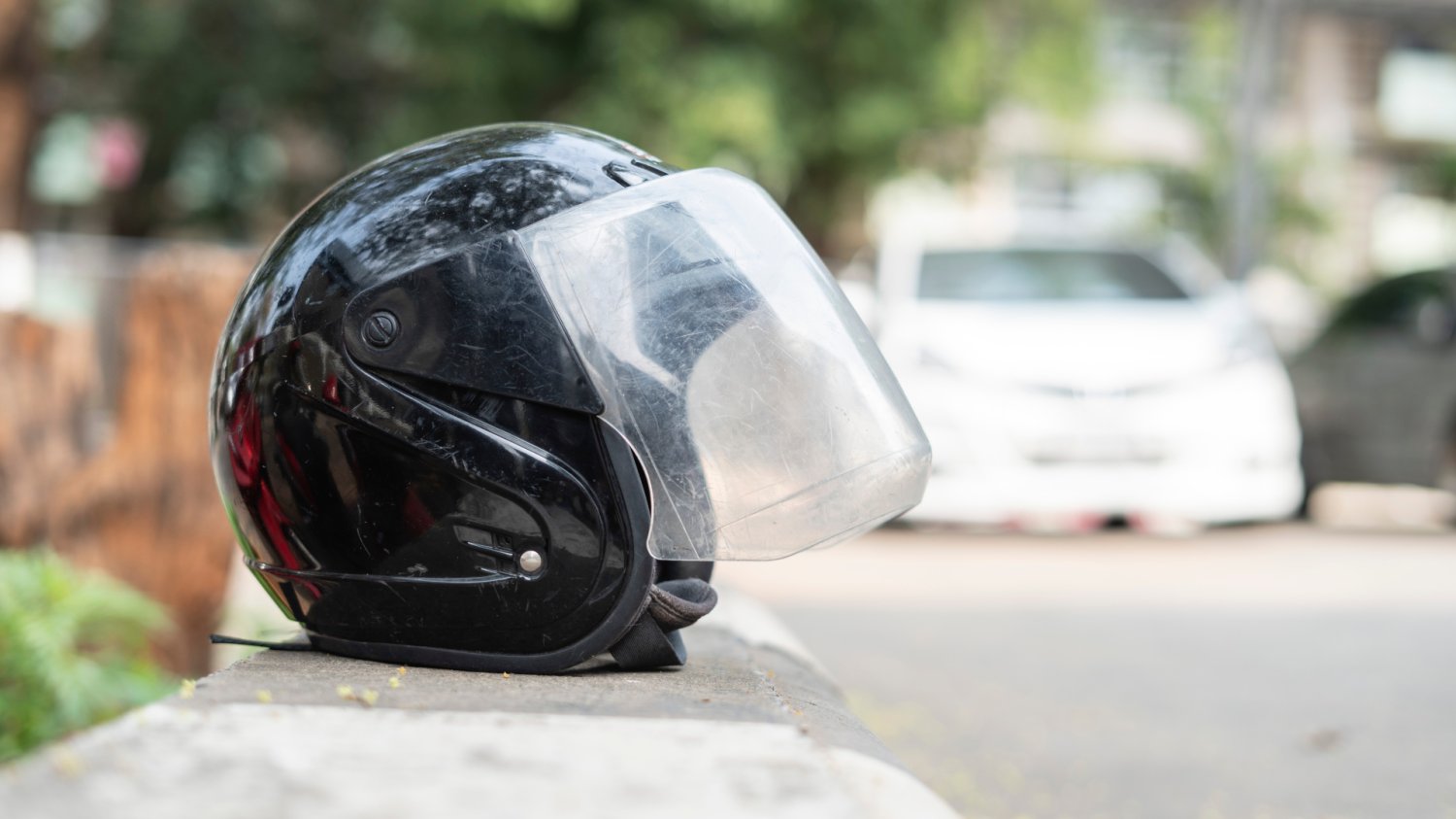 Kask na asfalcie to wezwanie o pomoc na drodze Czarny kask motocyklowy leżący na asfalcie na poboczu drogi symbolizujący awarię.
