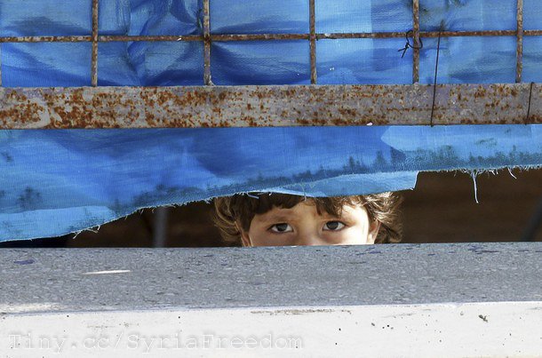 A Syrian refugee girl looks out from behind the fence at Yayladagi refugee camp in Hatay province near the Turkish-Syrian border April 10, 2012.