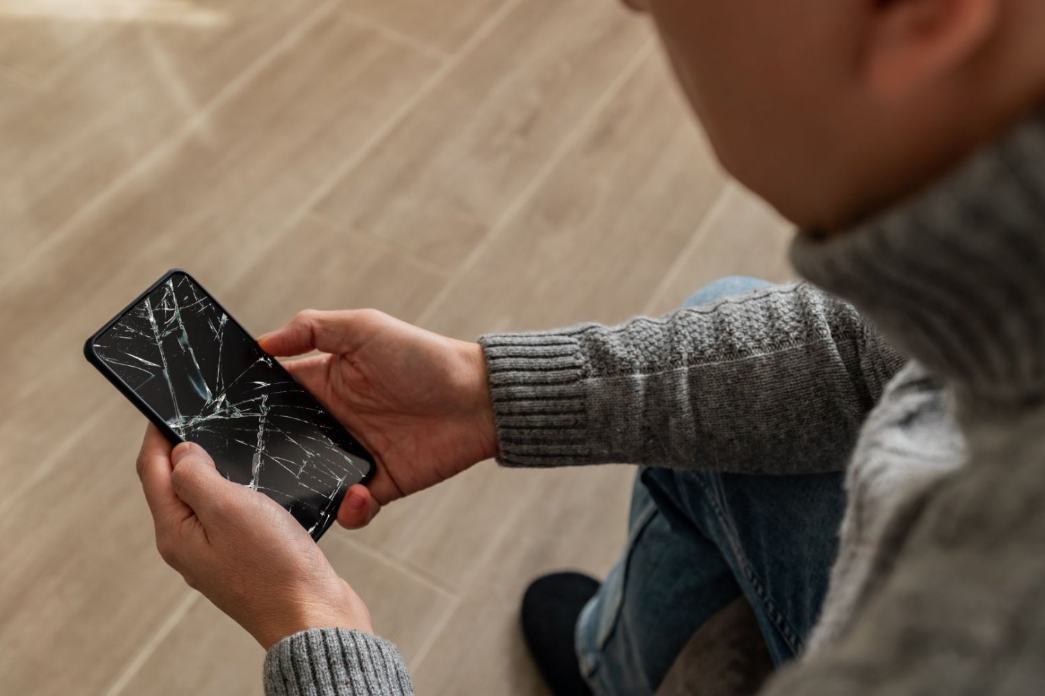 Psujesz telefon i nawet o tym nie wiesz. Unikaj siedmiu głównych błędów Mężczyzna trzymający w dłoniach popsuty telefon.