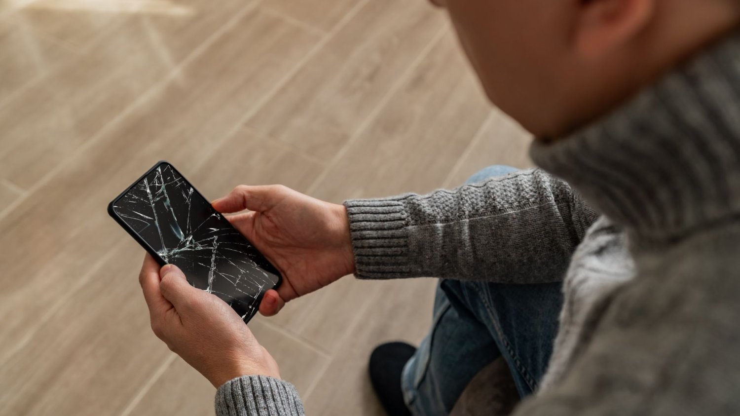Psujesz telefon i nawet o tym nie wiesz. Unikaj siedmiu głównych błędów Mężczyzna trzymający w dłoniach popsuty telefon.