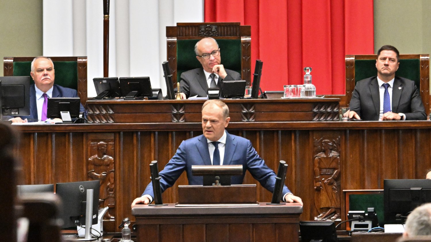 Najnowszy sondaż partyjny i podział mandatów w Sejmie Donald Tusk przemawia w Sejmie. Wykresy najnowszego poparcia dla partii politycznych pokazują zmianę podziału mandatów. W tle posłowie podczas głosowania.