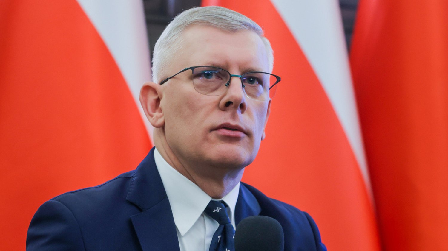 Nocne zamawianie pizzy do Cenckiewicza i nękanie dziennikarzy TV Republika 2026 Sławomir Cenckiewicz na tle biało-czerwonej flagi. Historyk padł ofiarą prowokacji