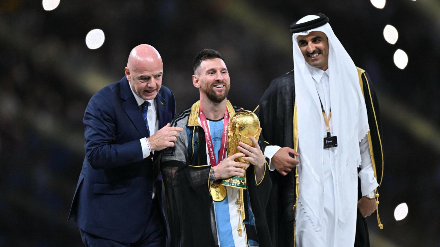 Gianni Infantino, Lionel Messi i Tamim bin Hamad Al Thani na podium po finale MŚ 2022. Argentyńczyk przywdział biszt.