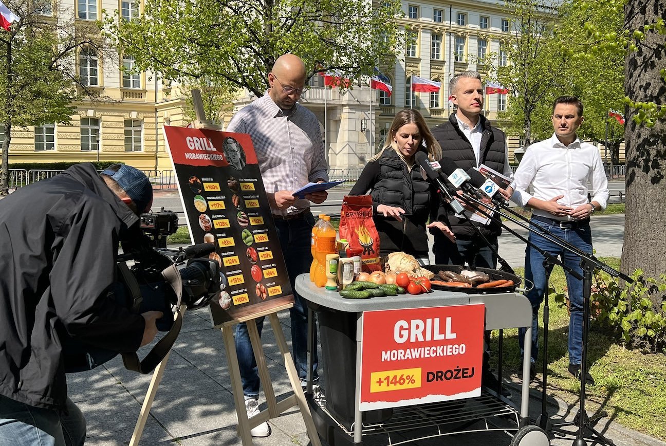 Posłanka i posłowie opozycji podczas akcji "Grill Morawieckiego" przed KPRM w Warszawie. Politycy mówią, że majówka będzie droższa o 146 proc.