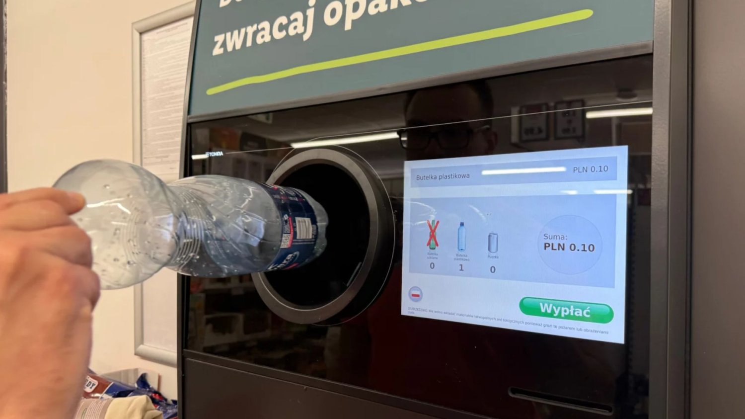 Osoba wrzucająca butelkę do automatu kaucyjnego.
