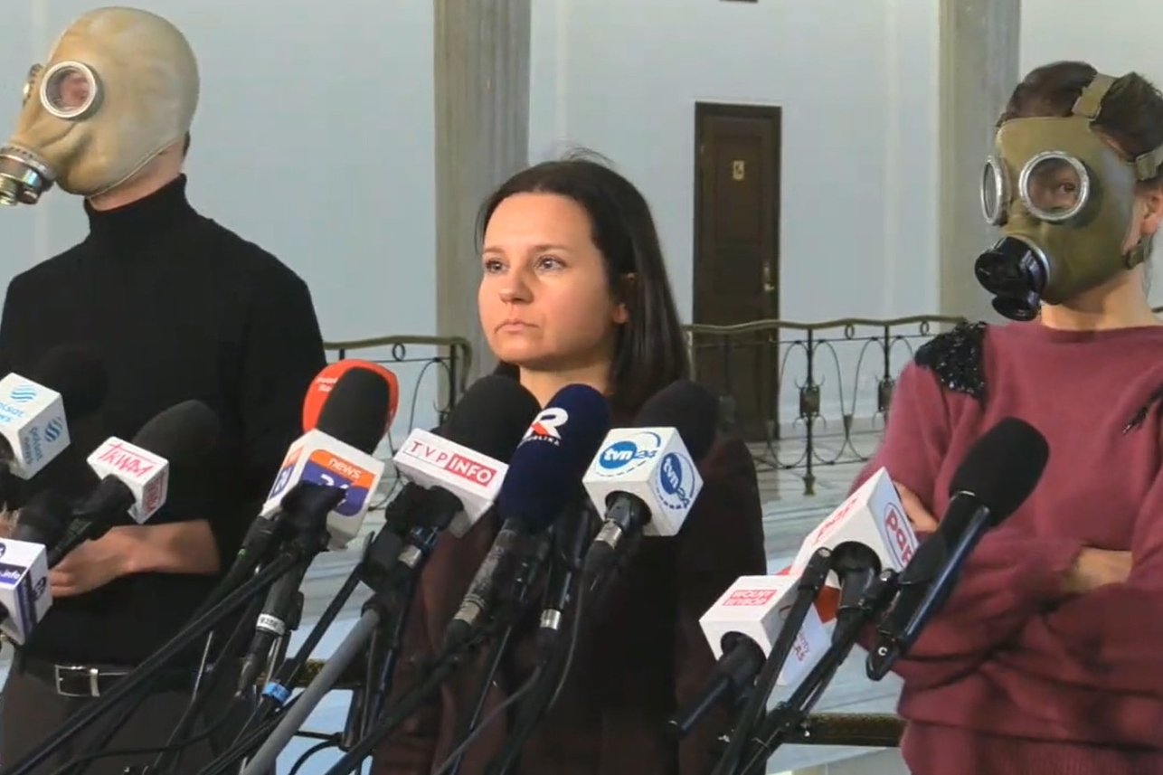 Osoby w maskach przeciwgazowych podczas konferencji partii Zieloni.