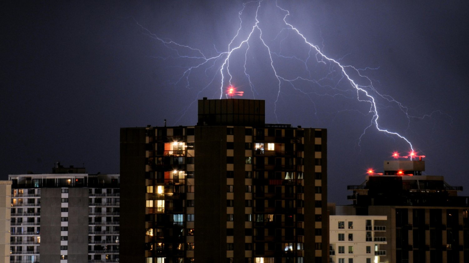 błyskawica nad blokowiskiem panorama blokowiska nocą z ogromną błyskawicą na niebie