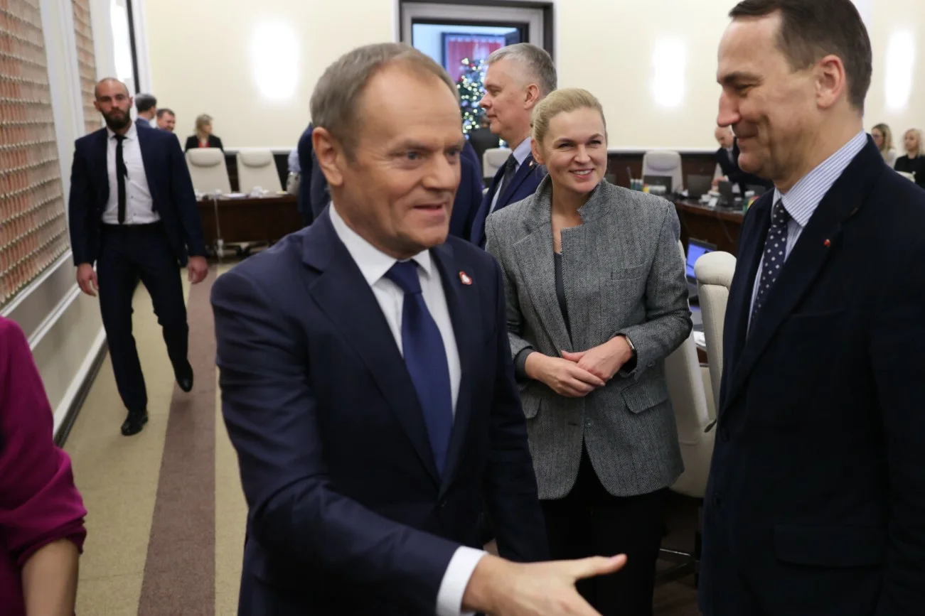 Premier Donald Tusk na posiedzeniu Rady Ministrów (27.12.2023) Właśnie uścisnął dłoń ministry edukacji Barbary Nowackiej i ministra spraw zagranicznych Radosława Sikorskiego. Premier Donald Tusk na posiedzeniu Rady Ministrów (27.12.2023) Właśnie uścisnął dłoń ministry edukacji Barbary Nowackiej i ministra spraw zagranicznych Radosława Sikorskiego.