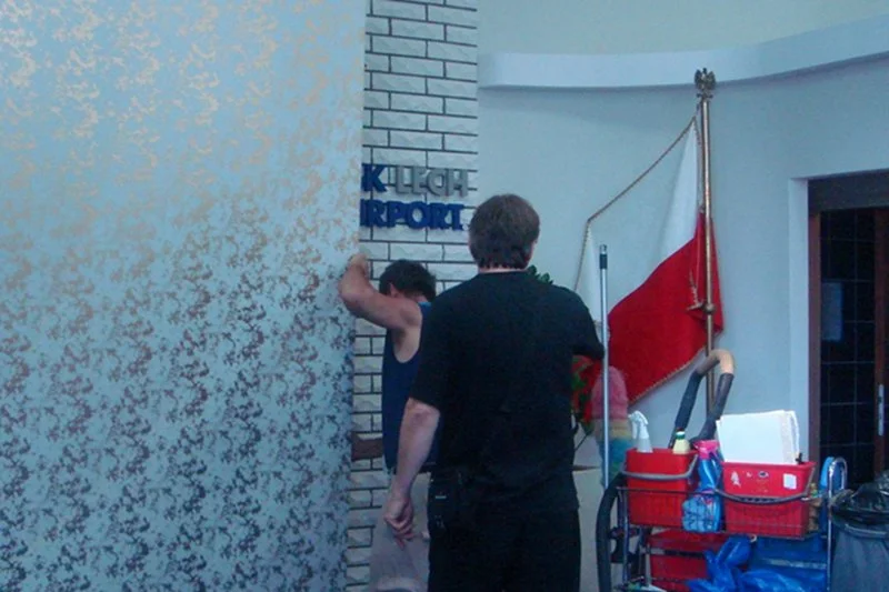 Moment zasłaniania tablicy z nazwiskiem Lecha Wałęsy. Były prezydent informuje, że operację tę przeprowadzono przed wizytą Lecha Kaczyńskiego na gdańskim lotnisku.