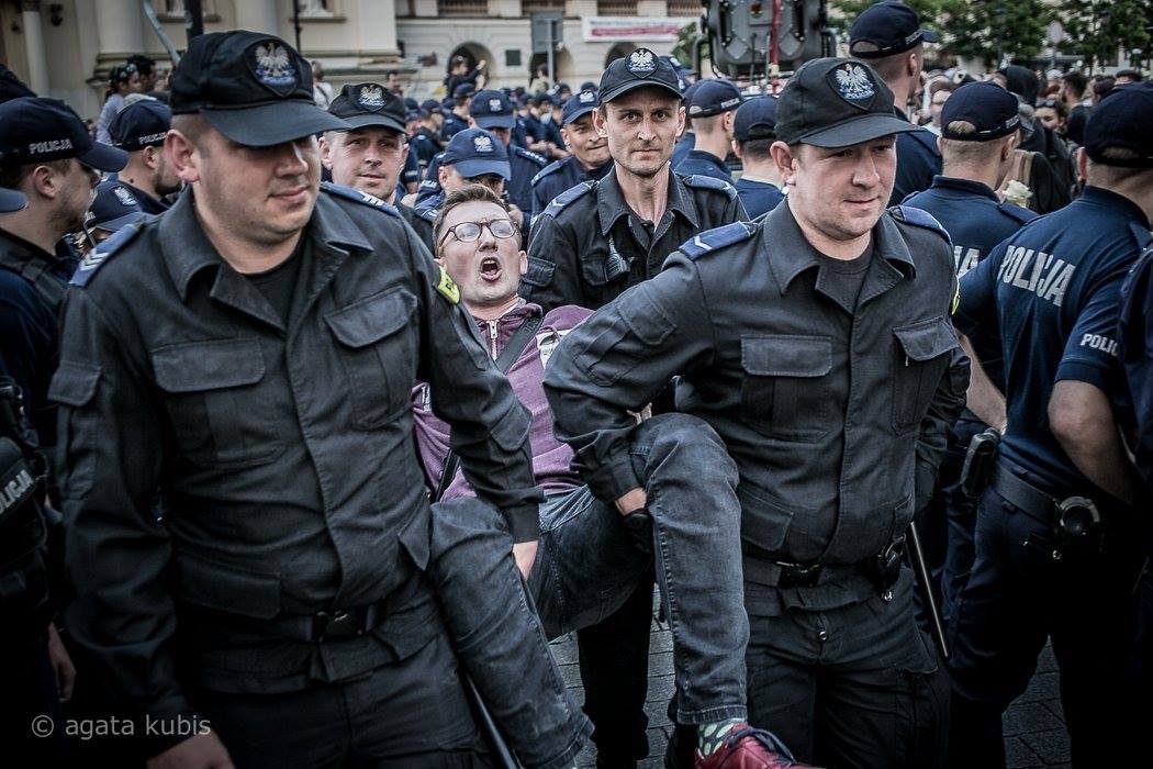Młody mężczyzna wynoszony przez policjantów z blokady przy Krakowskim Przedmieściu w Warszawie.
