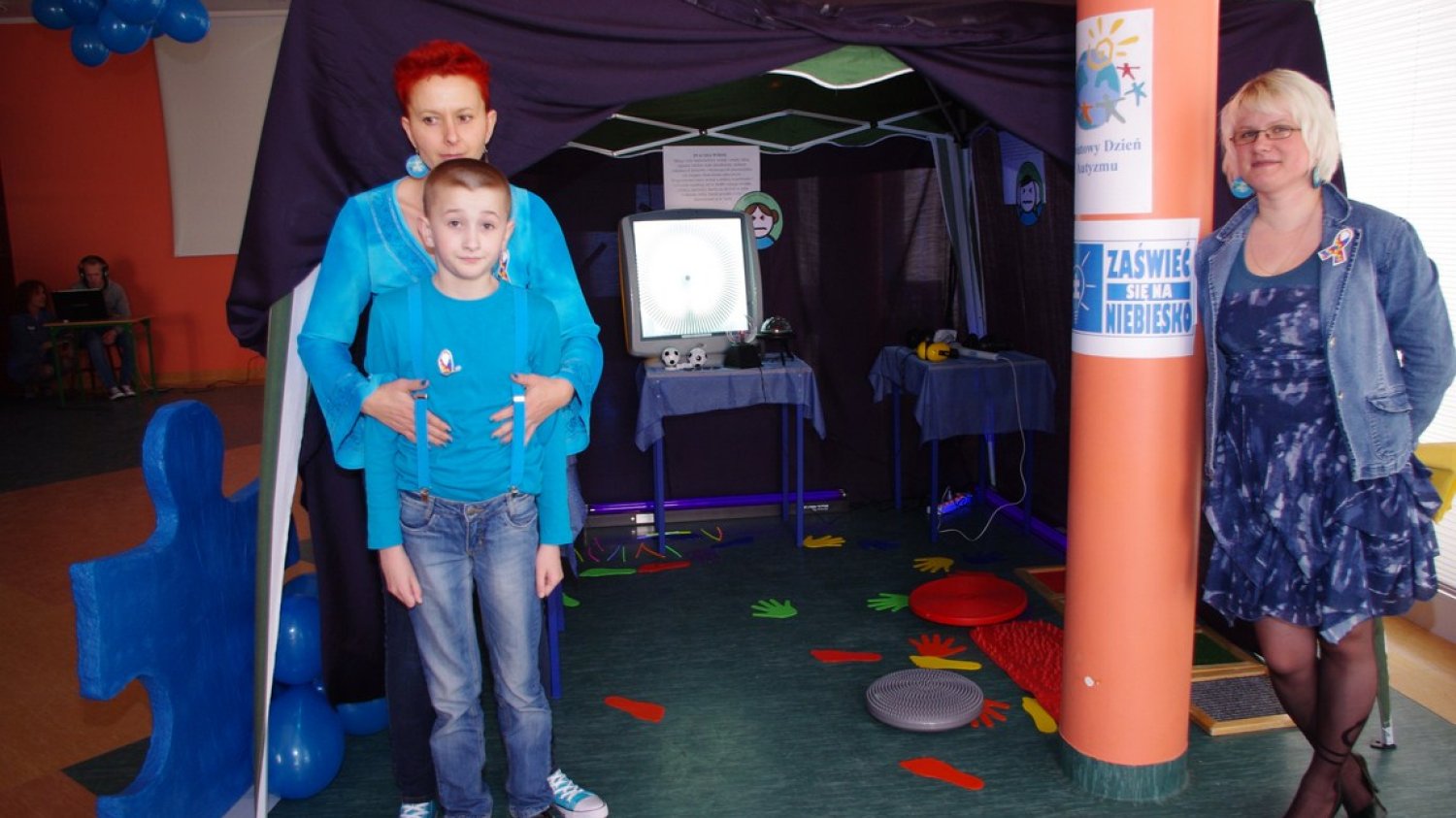Niebieski to kolor autyzmu, identyfikator mógłby być więc przykładowo znaczkiem w tym kolorze. Na zdjęciu od lewej autystyczny Jurek z mamą Elizą oraz jego wychowawczyni Magdalena Zbróg