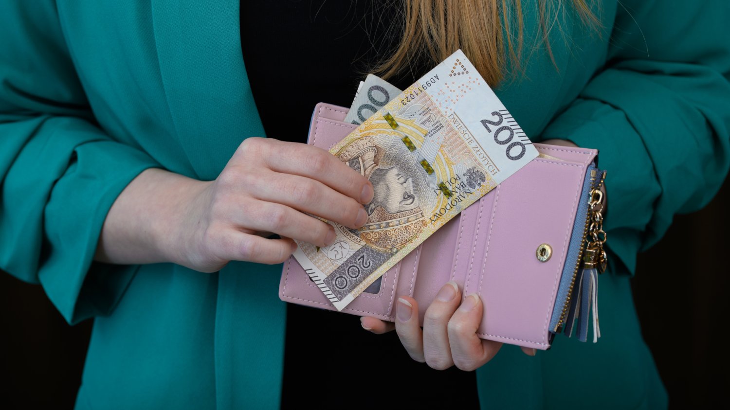 Kobieta w marynarce trzymająca portfel i gotówkę