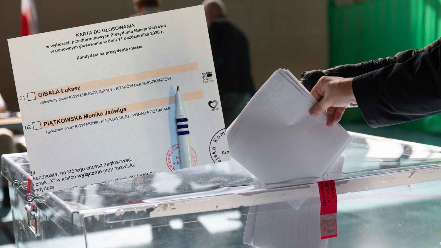 karta do głosowania z wyborów 11 października 2026 r., w tle osoba wrzucająca głos do urny