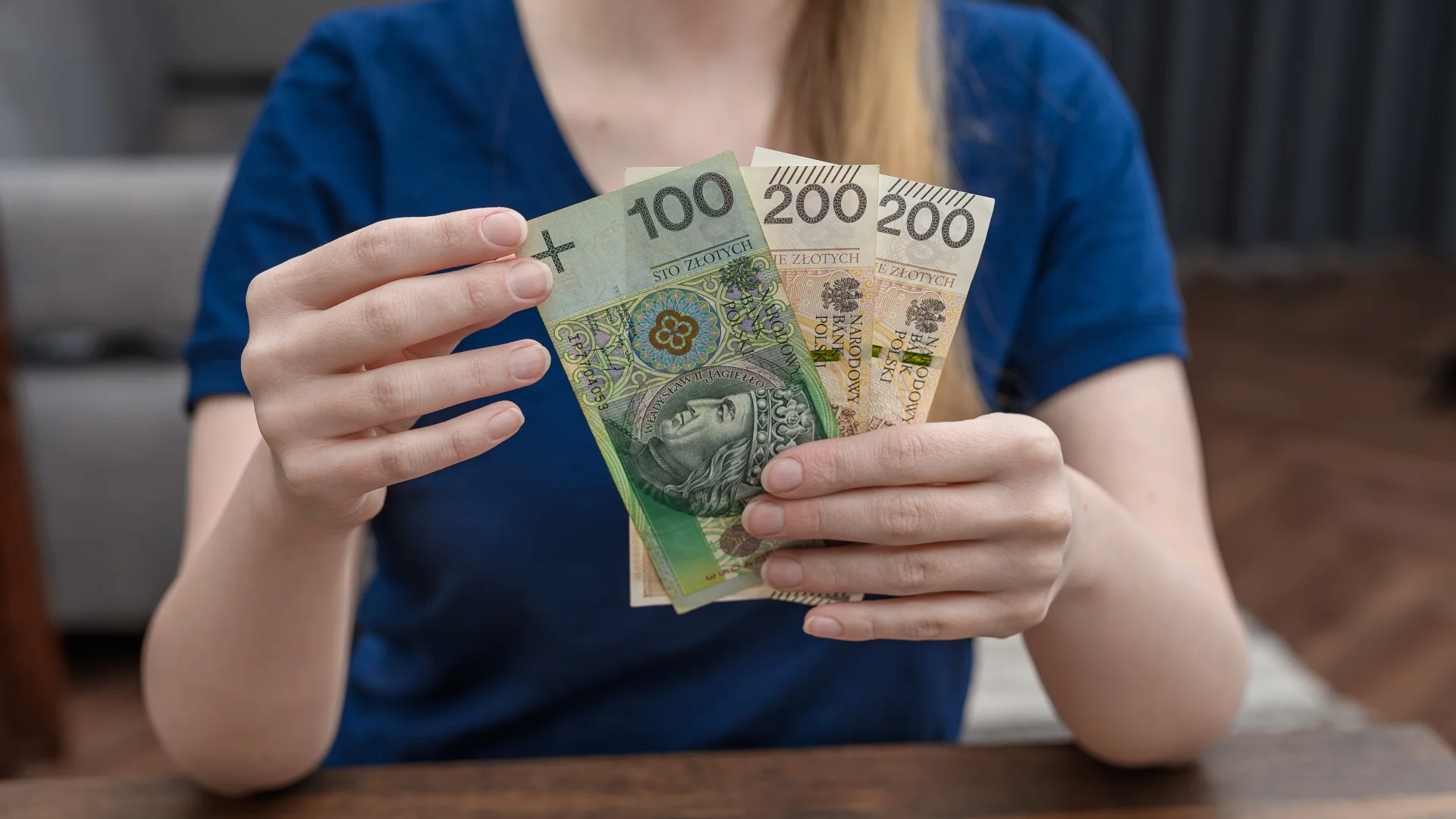 500 zł odsetek miesięcznie. Ile trzeba mieć w banku na lokacie? Kobieta pokazująca banknoty warte 500 zł