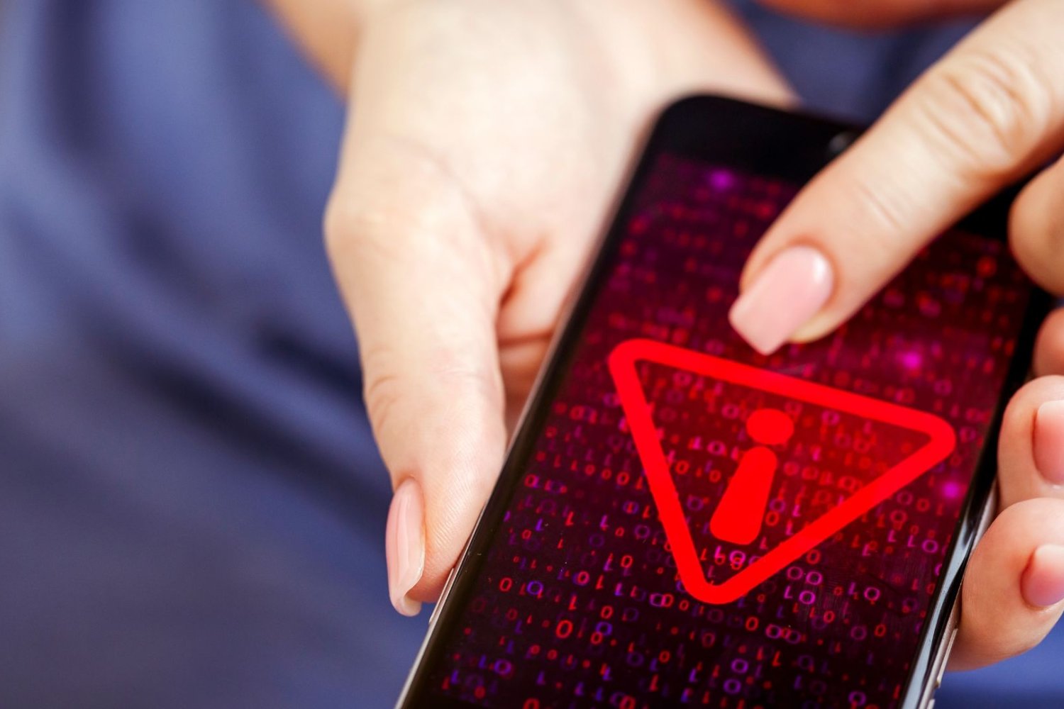 Baza MyDr wyciekła do sieci. Zagrożenie może jednak czyhać gdzie indziej Kobieta trzyma telefon, czerwony wykrzynik na ekranie