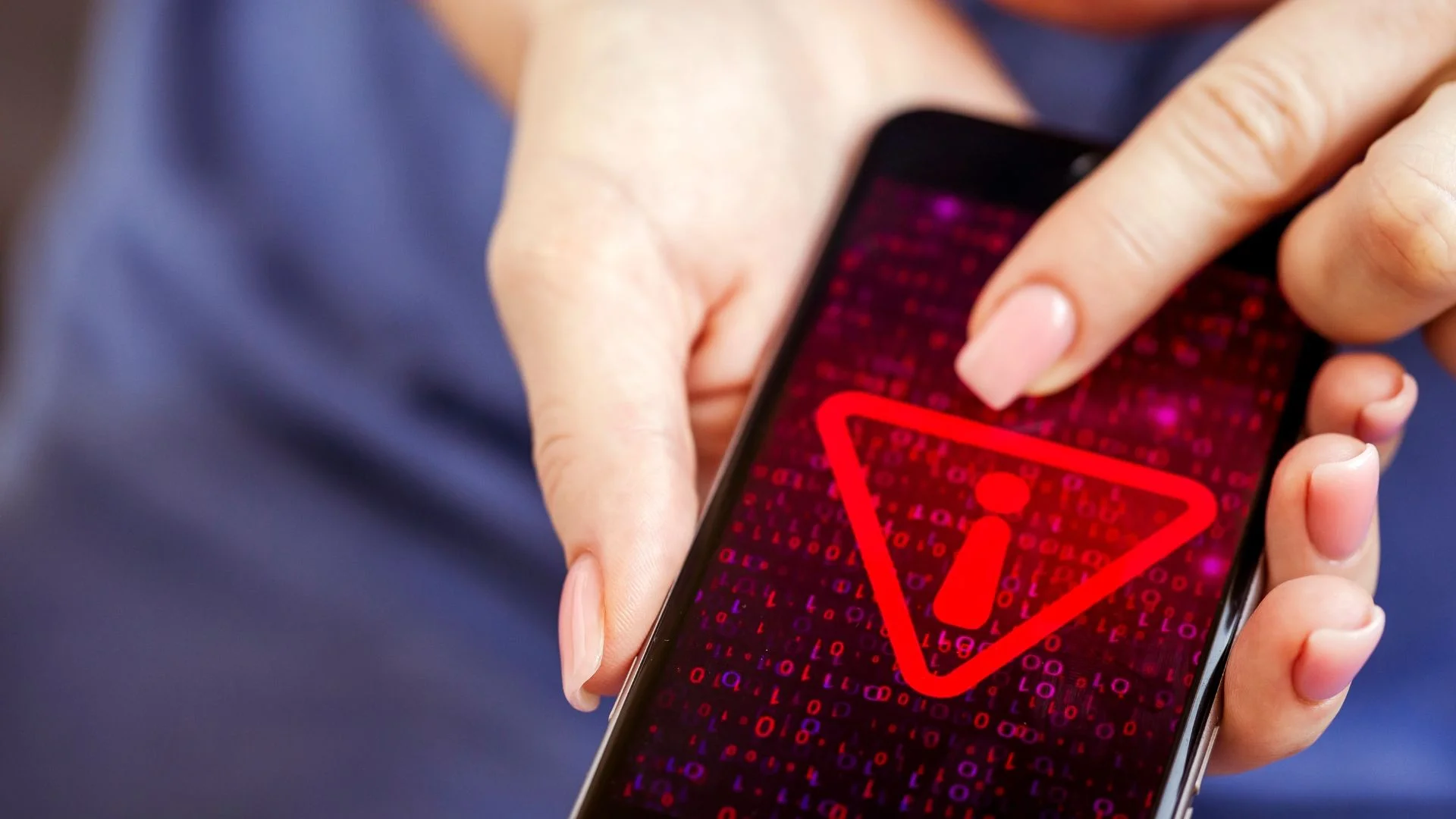 Kobieta trzyma telefon, czerwony wykrzynik na ekranie