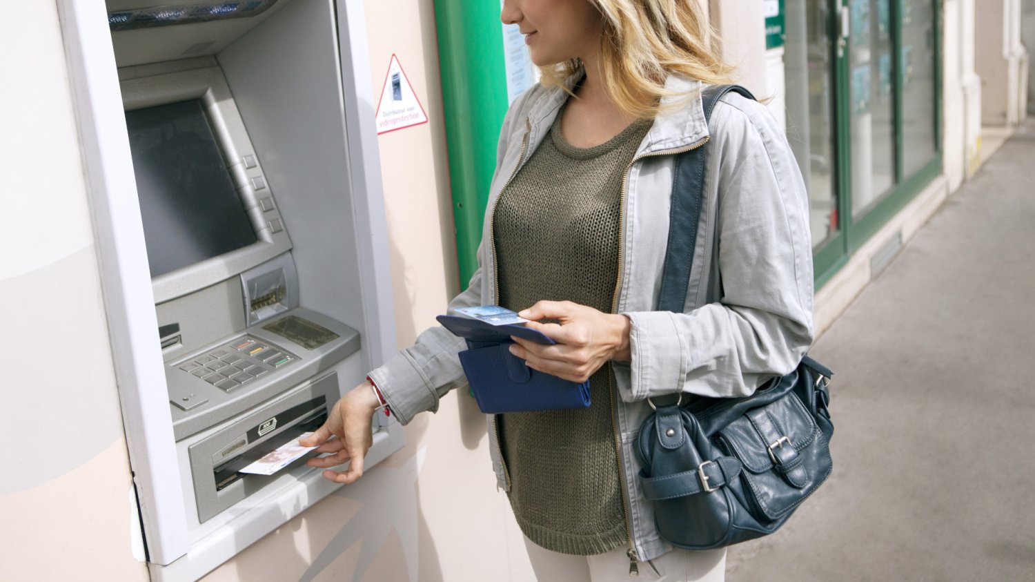 Prowizja za wypłatę z bankomatu. Ile kosztuje? Kobieta wypłaca pieniądze z bankomatu
