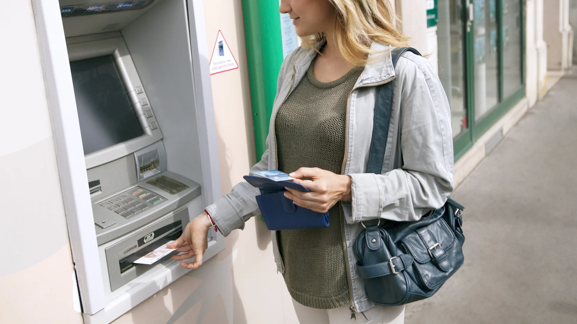 Prowizja za wypłatę z bankomatu. Ile kosztuje? Kobieta wypłaca pieniądze z bankomatu