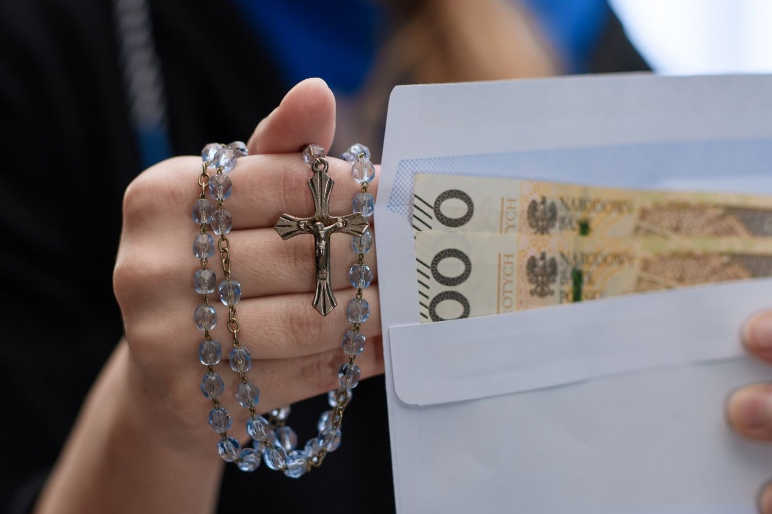 Kobieta z różańcem i kopertą z pieniędzmi