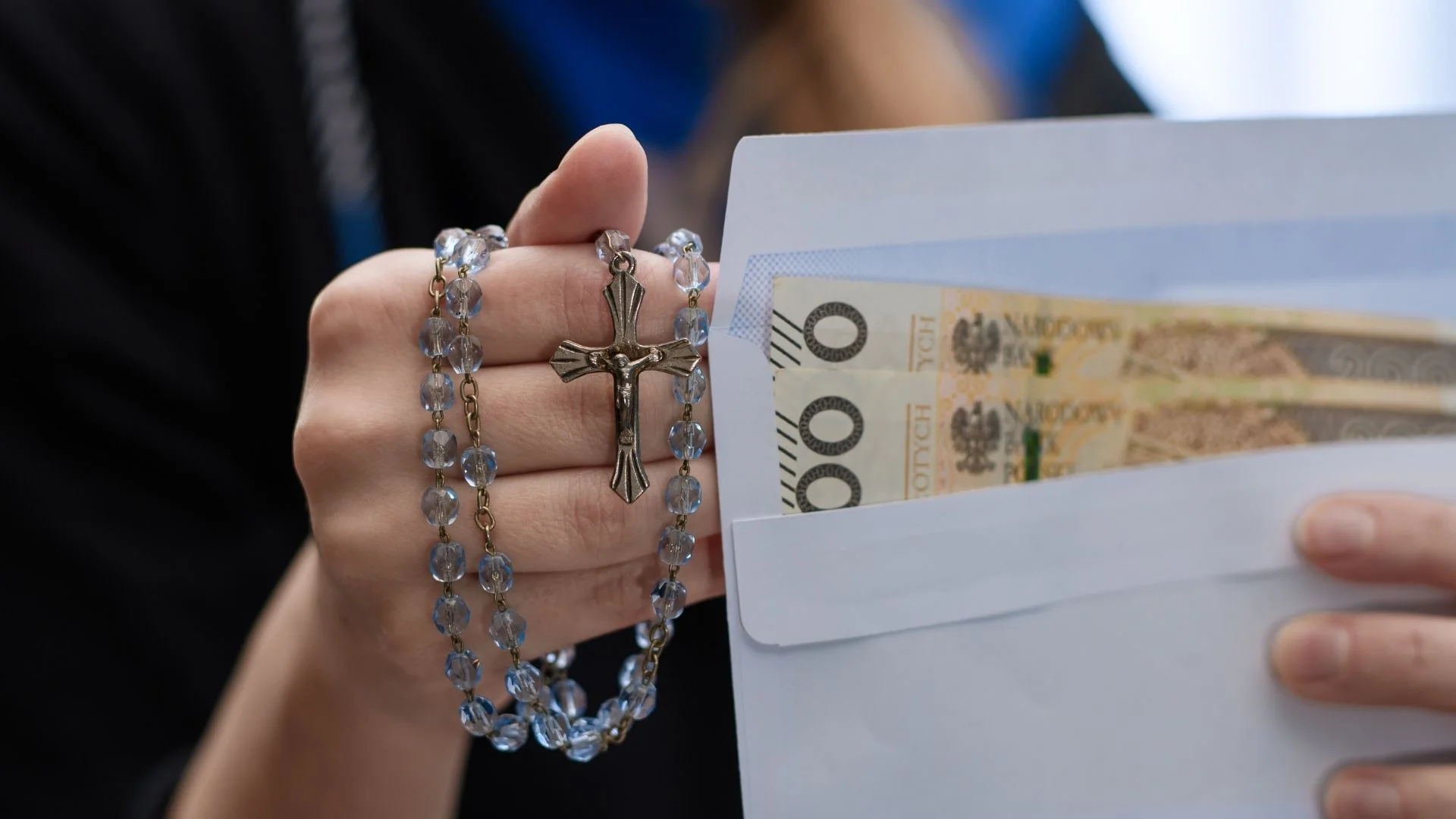 Kobieta trzyma w dłoni różaniec i kopertę z gotówką Kobieta z różańcem i kopertą z pieniędzmi