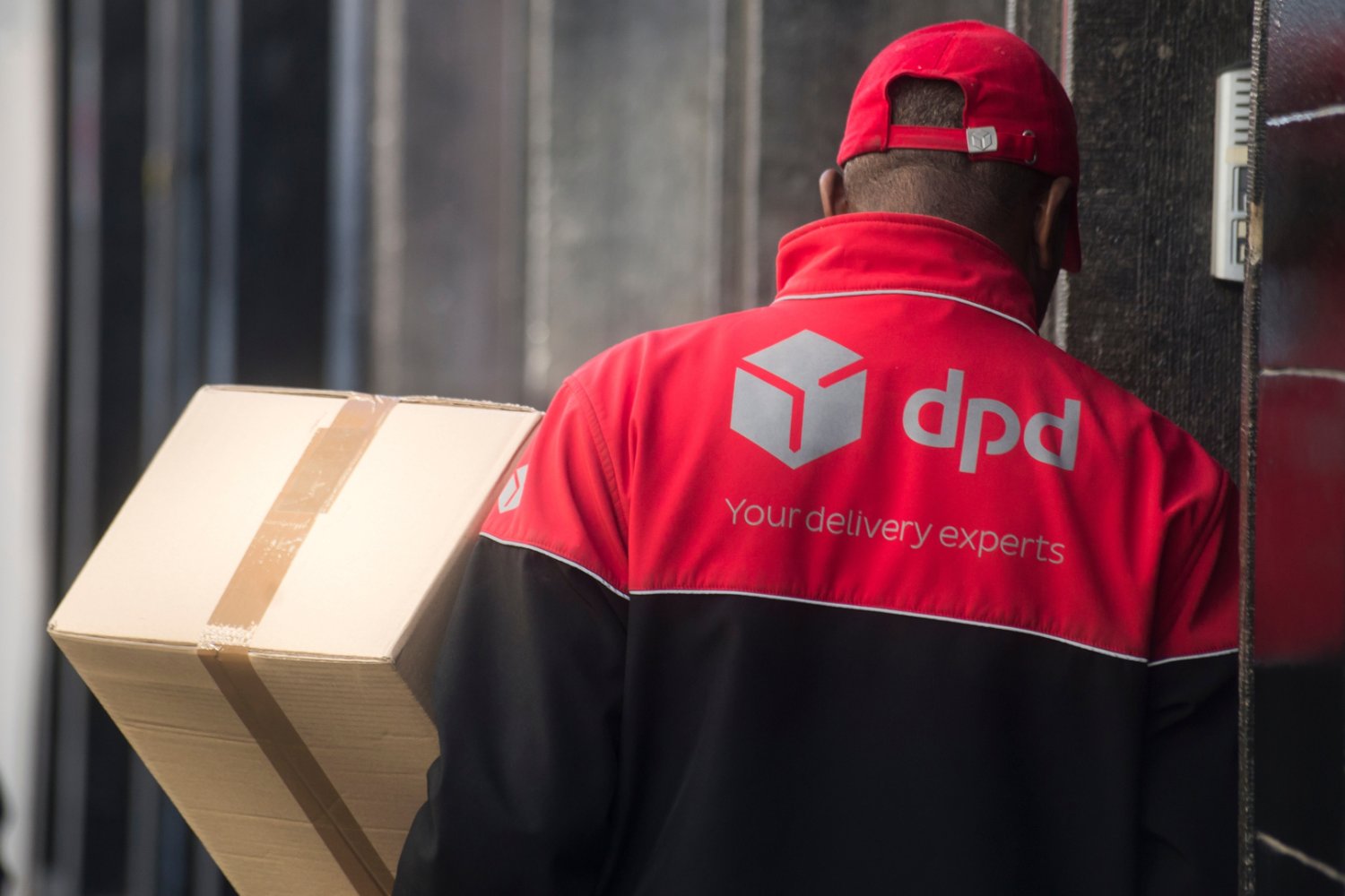 Kurier niosący przesyłkę kartonową jako ostrzeżenie przed oszustwem na DPD