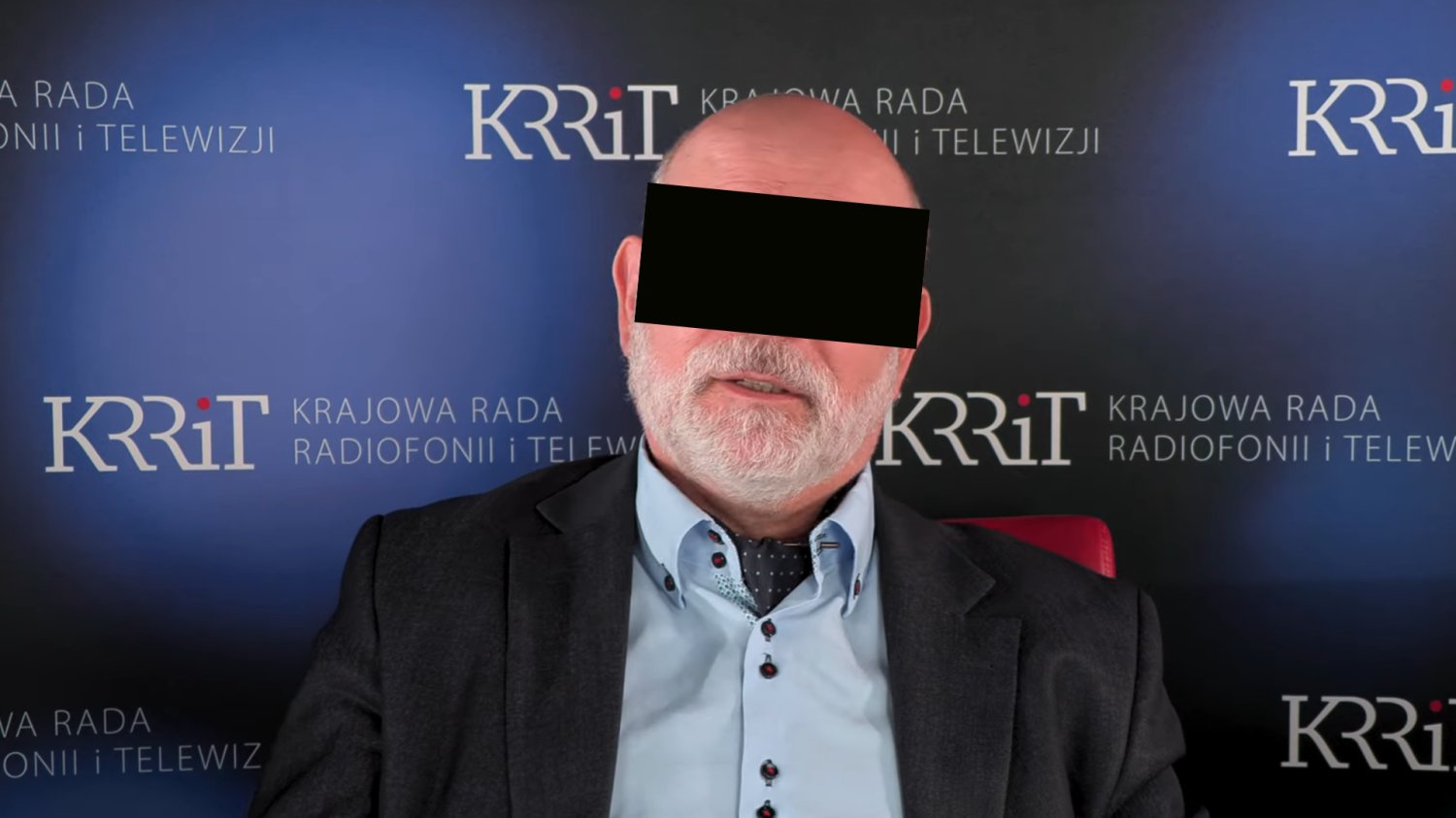 Maciej Ś. na tle bannerów KRRiT