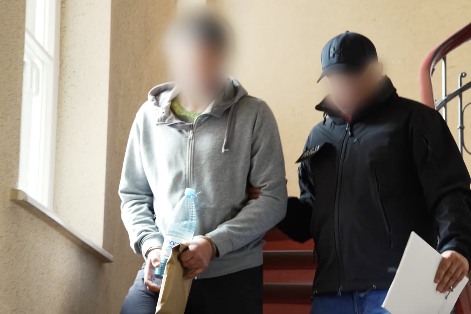 Mężczyzna zatrzymany ws. zabójstwa 13-letniej Izy prowadzony przez policjanta