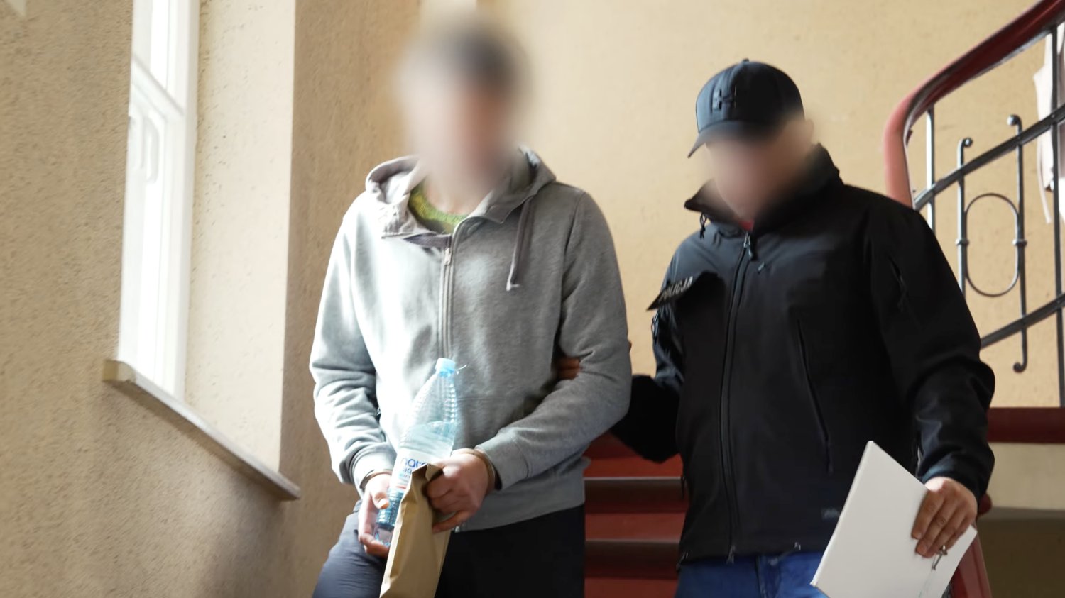 Mężczyzna zatrzymany ws. zabójstwa 13-letniej Izy prowadzony przez policjanta