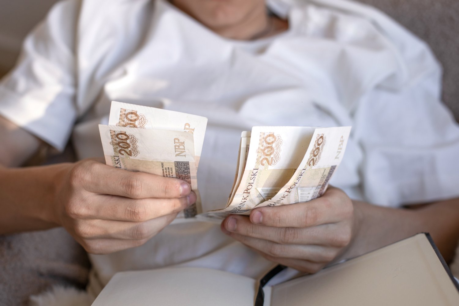 Osoba licząca pieniądze w łóżku