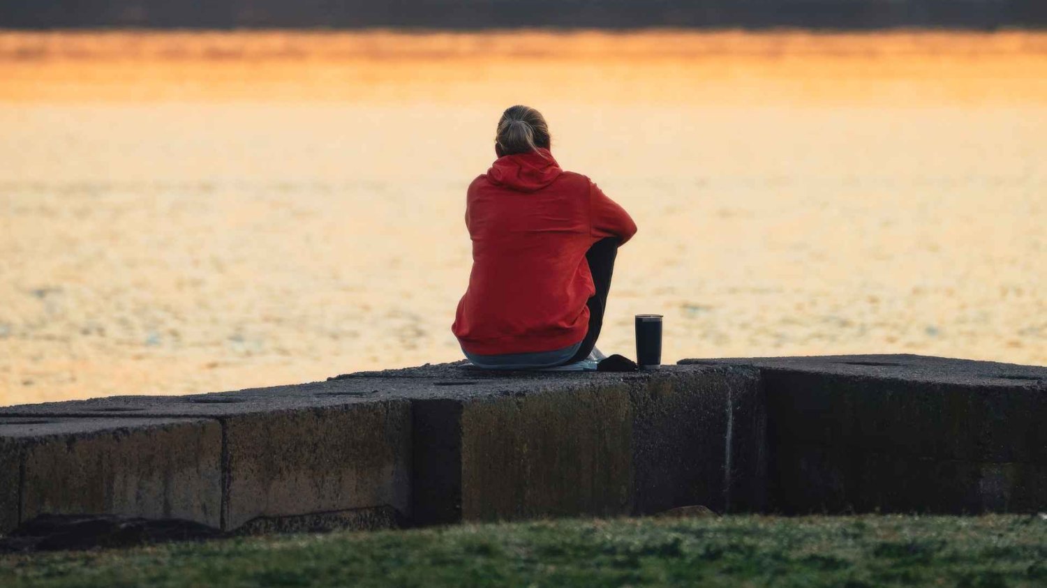Osoba w czerwonej kurtce siedząca samotnie