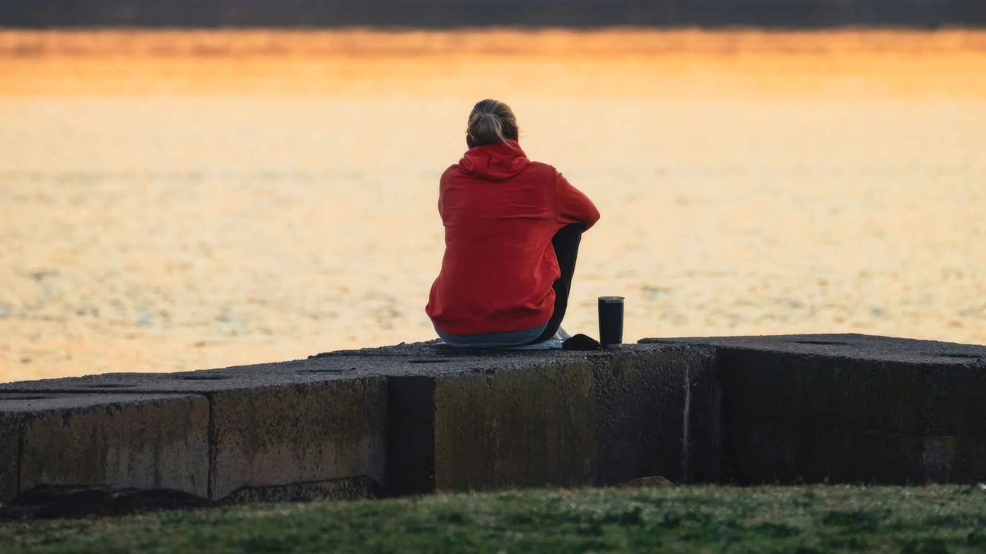 Osoba w czerwonej kurtce siedząca samotnie