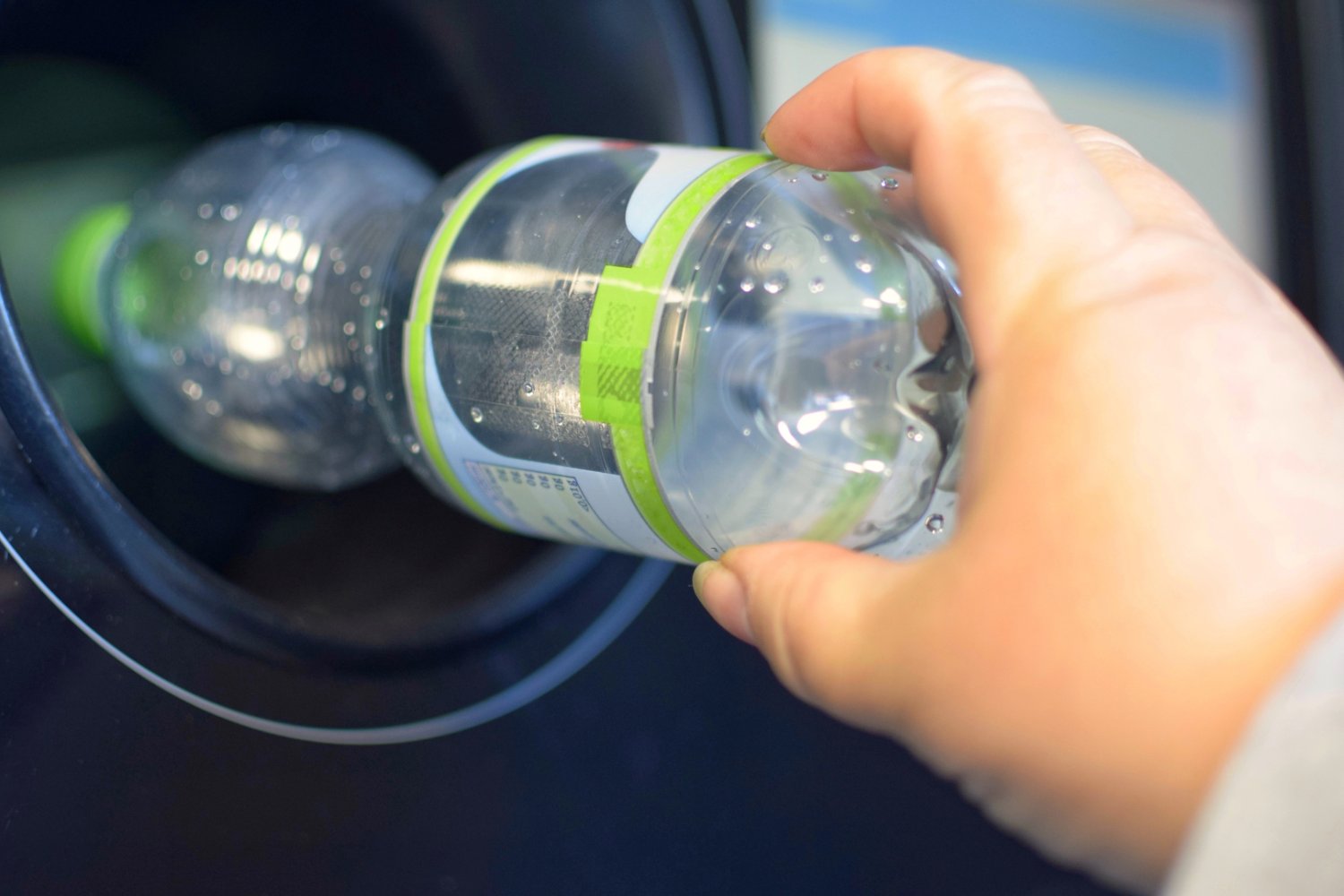 Osoba wrzucająca plastikową butelkę do recyklomatu