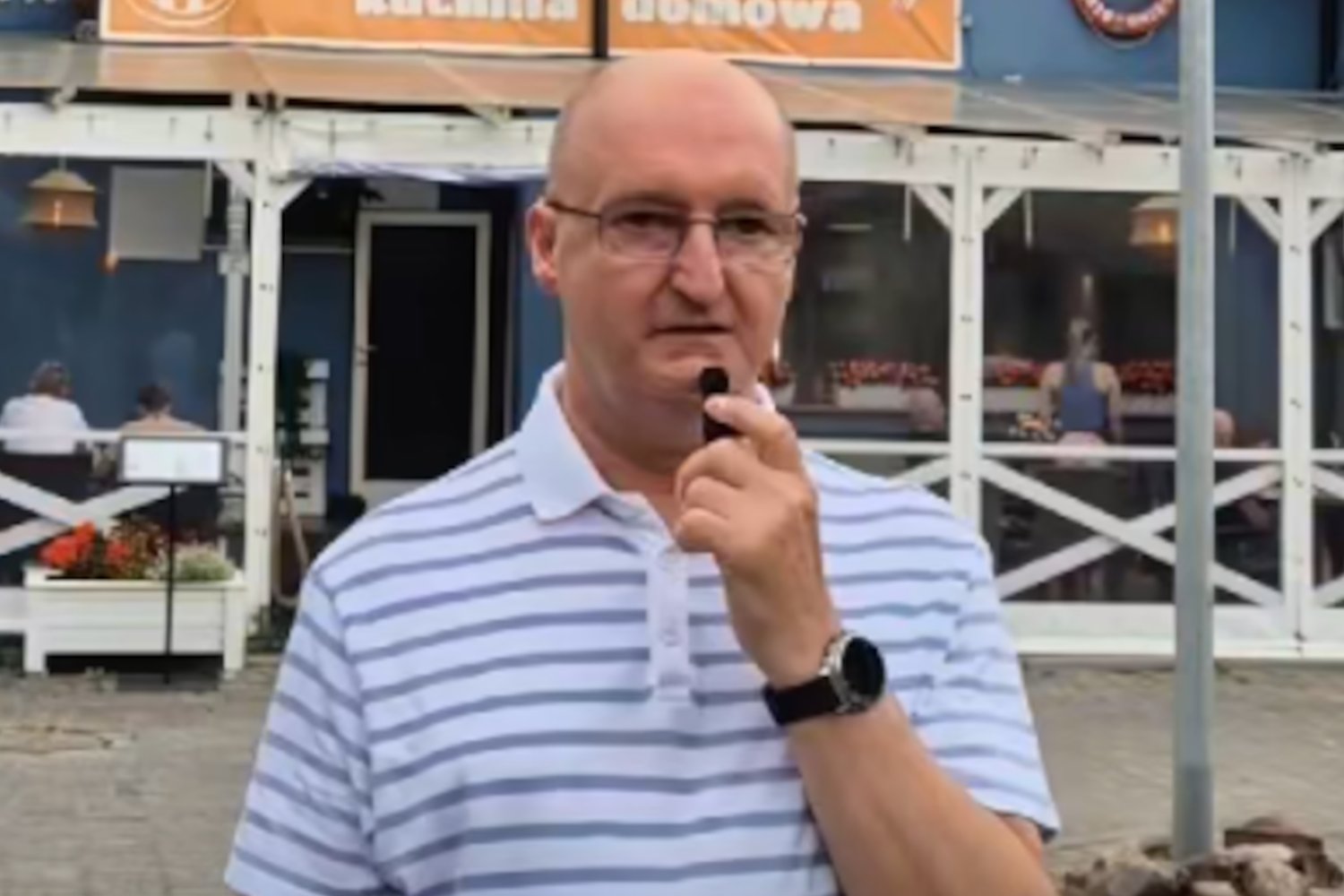 Piotr Wawrzyk nagrywa recenzje jedzenia na tle nadmorskiej restauracji