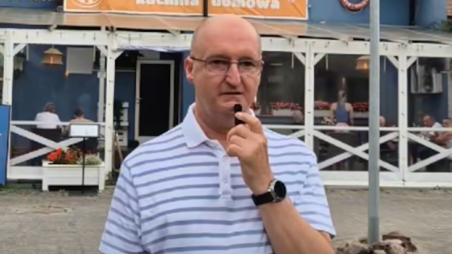 Piotr Wawrzyk nagrywa recenzje jedzenia na tle nadmorskiej restauracji
