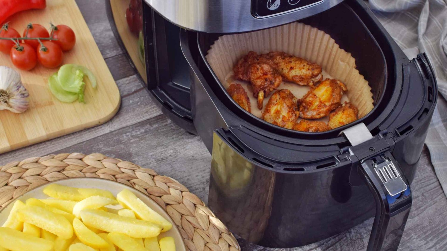 po lewej: krajalnica z pomidorami, czosnkiem, po lewej na dole: frytki, po prawej: czarny air-fryer