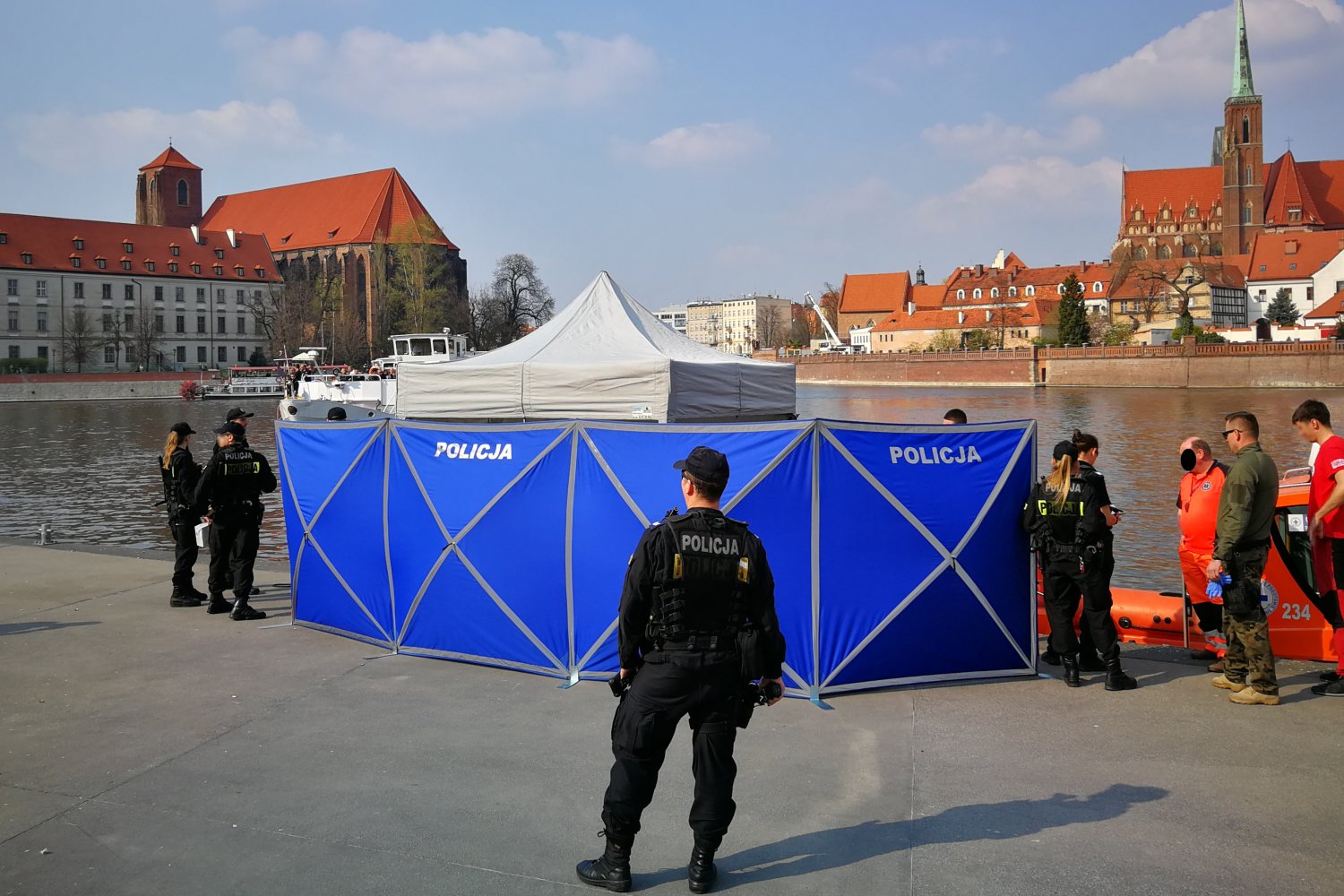 Dramatyczne statystyki policji w wakacje 2026. Woda groźniejsza niż drogi Policjanci i ratownicy na brzegi rzeki obok parawanu z napisem policja