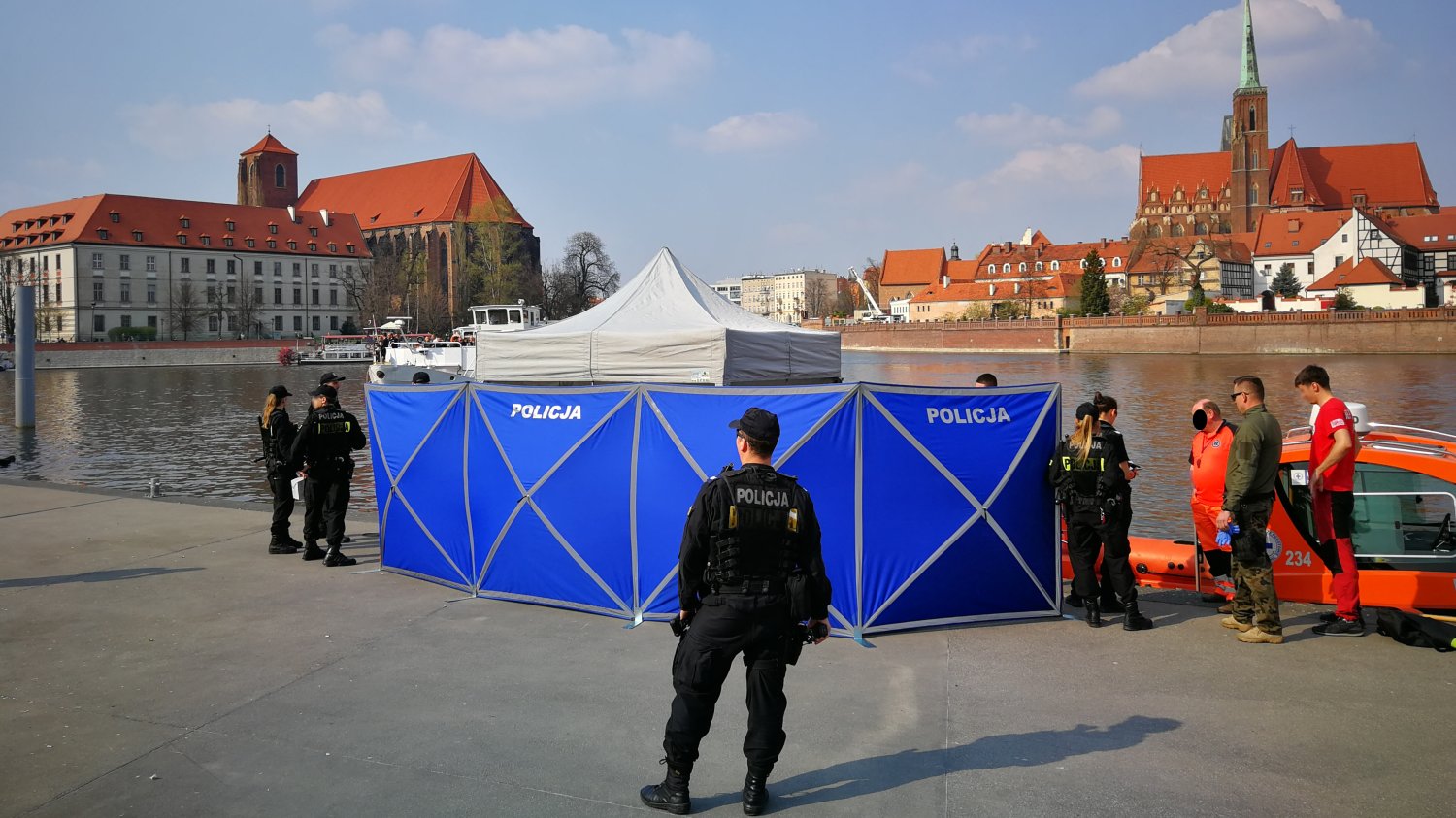Dramatyczne statystyki policji w wakacje 2026. Woda groźniejsza niż drogi Policjanci i ratownicy na brzegi rzeki obok parawanu z napisem policja
