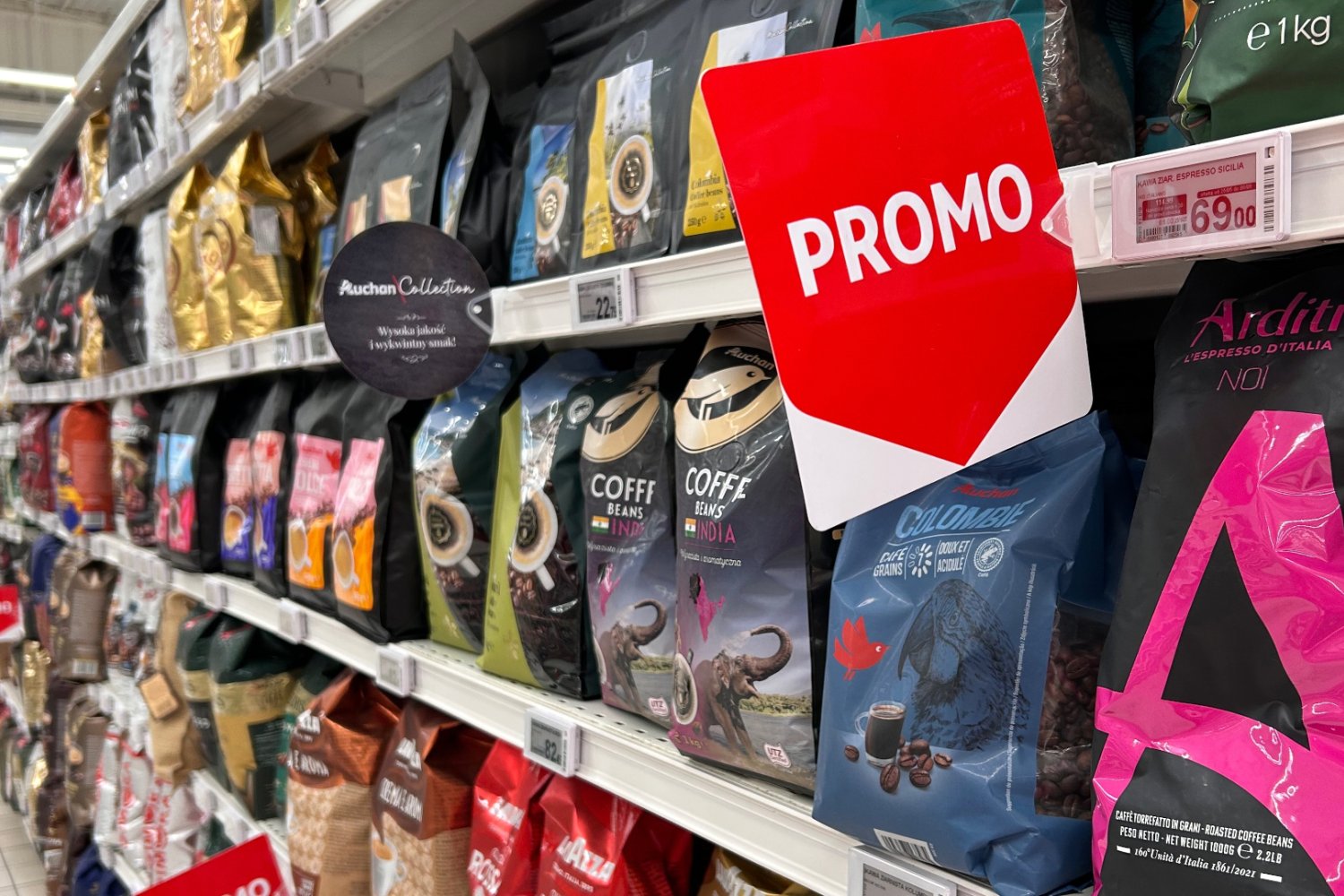Promocje na kawę w Biedronce, Lidlu i Aldi sierpień 2026 Półki z kawą w polskim supermarkecie i widoczne na nich etykiety promocyjne.