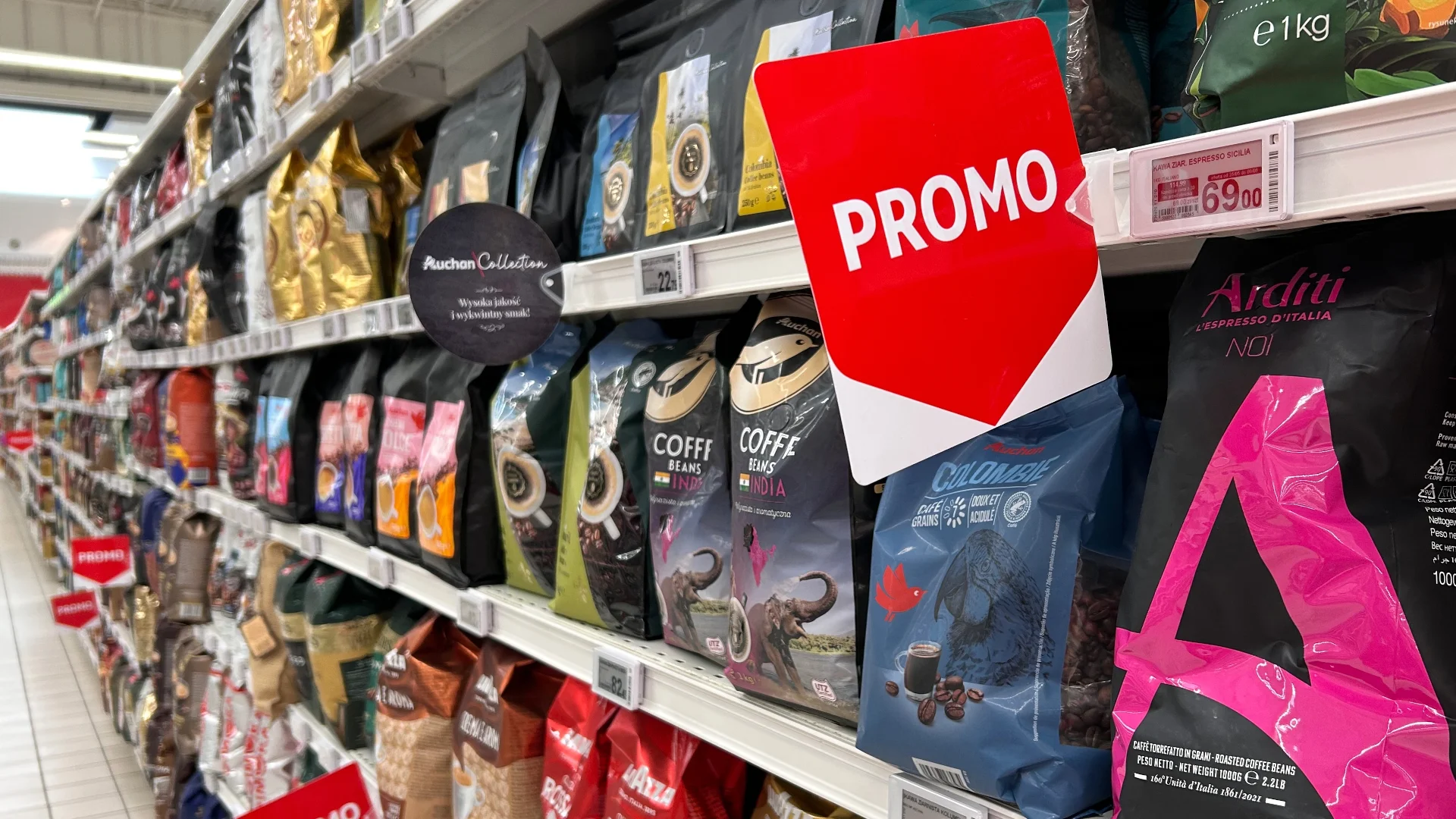 Promocje na kawę w Biedronce, Lidlu i Aldi sierpień 2026 Półki z kawą w polskim supermarkecie i widoczne na nich etykiety promocyjne.