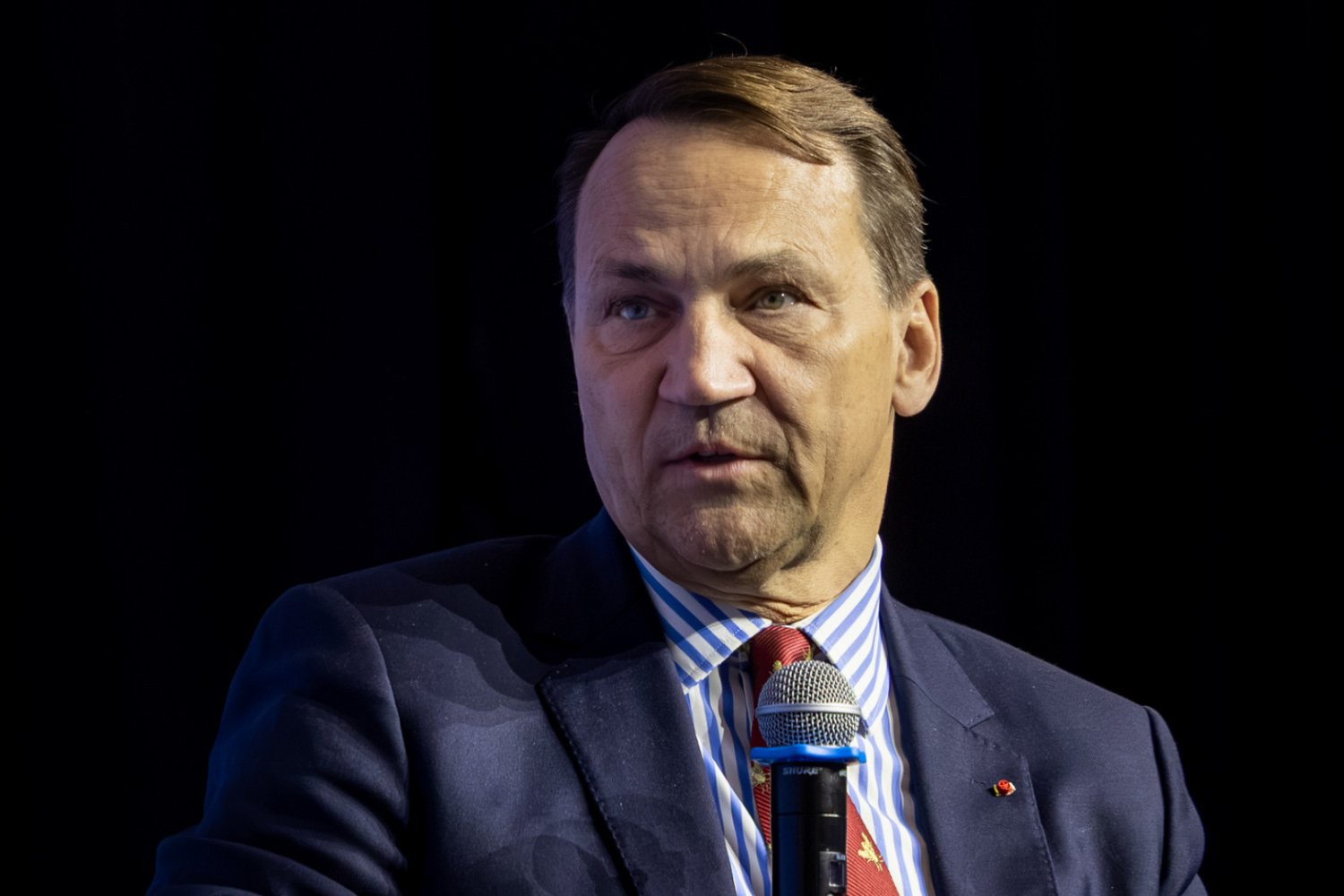 Radosław Sikorski na czarnym tle.