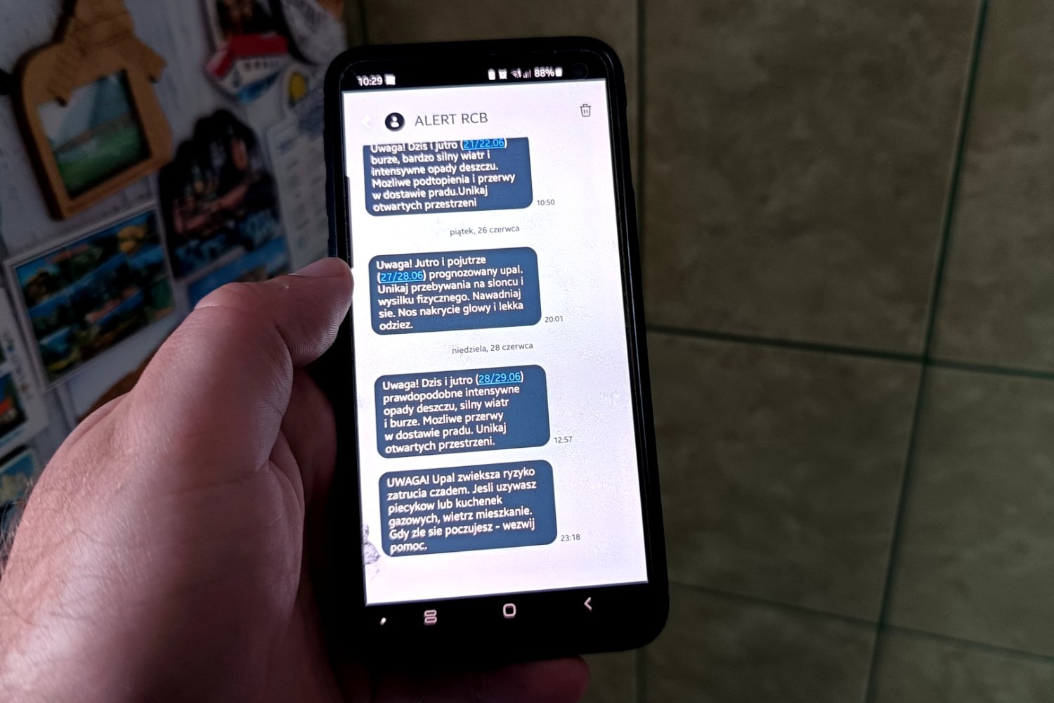 Ręka trzymająca smartfona z alertami RCB